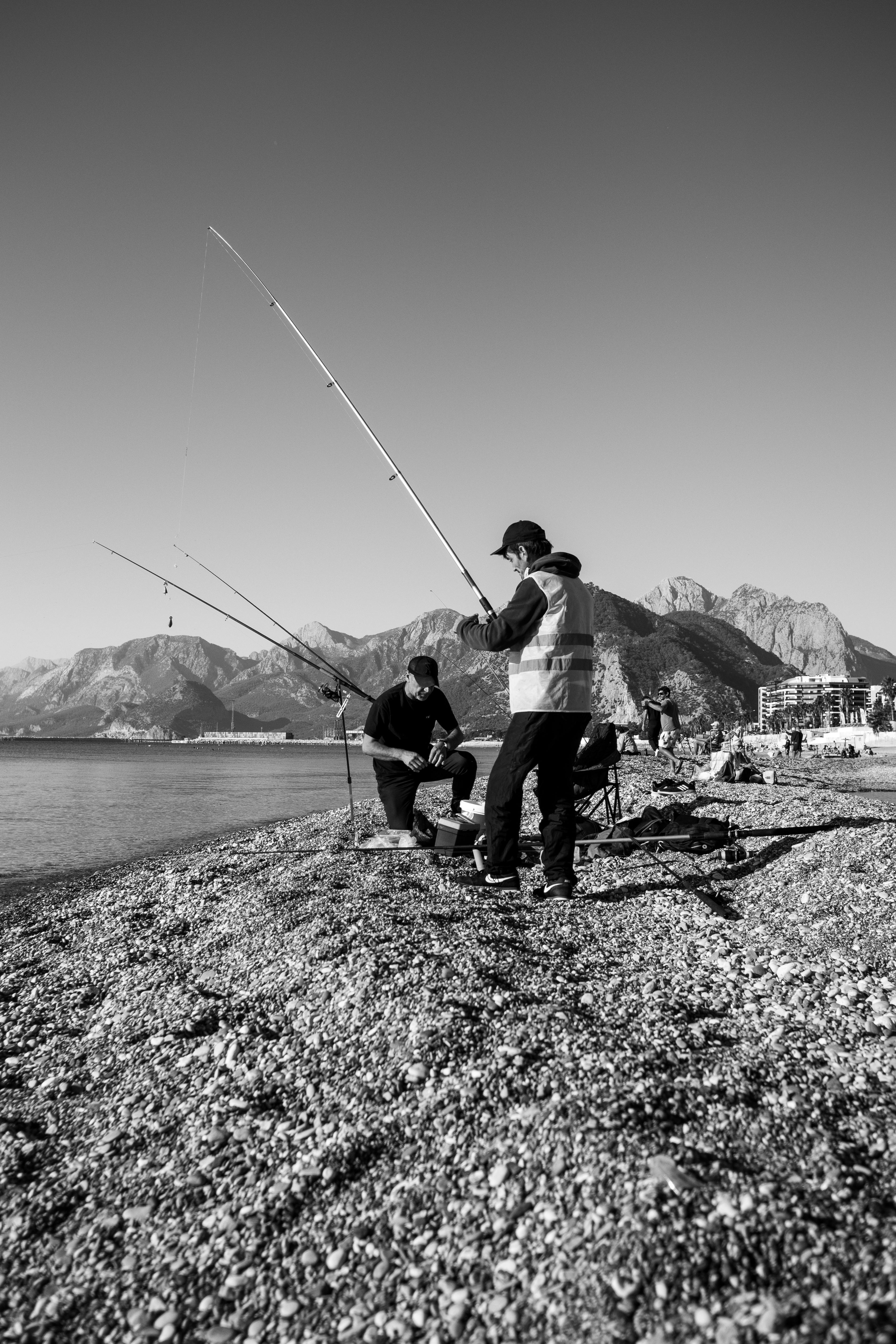 Two Men Fishing on Pebbly Beach