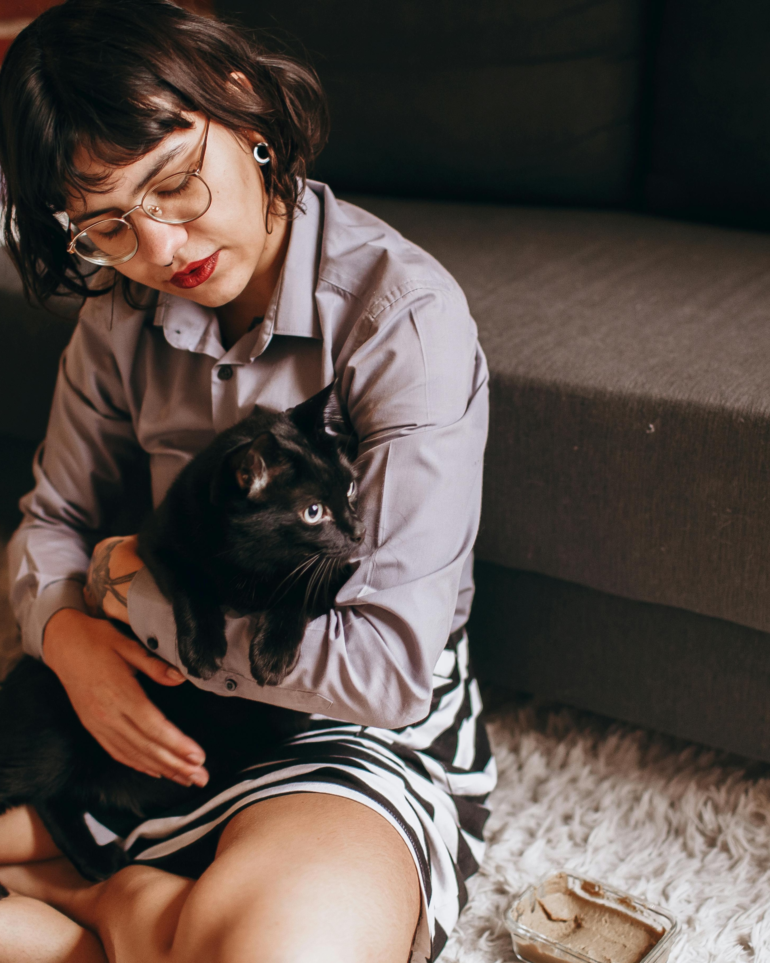 Woman Holding Black Cat At Home