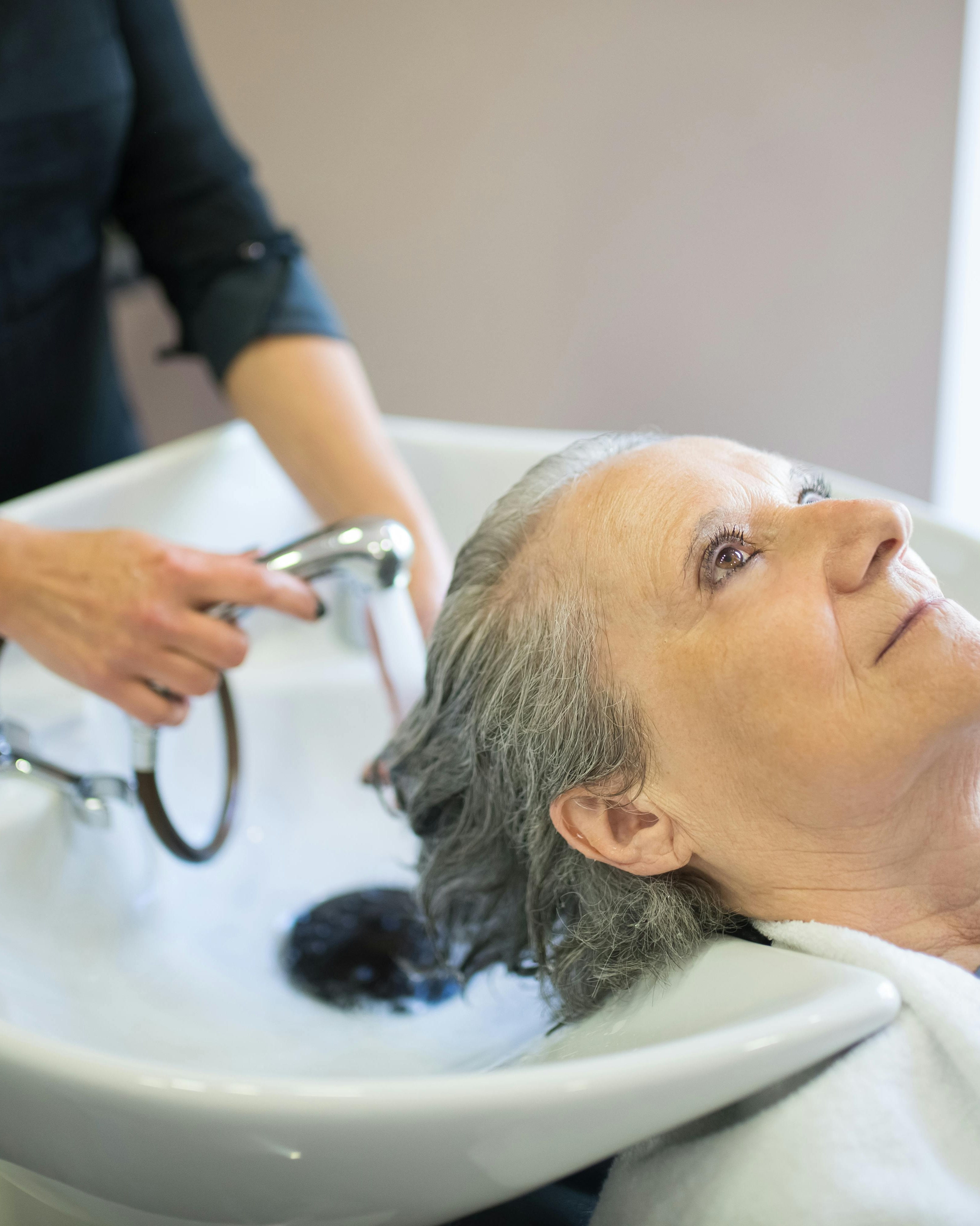 Senior Woman Getting Hair Washed At Salon