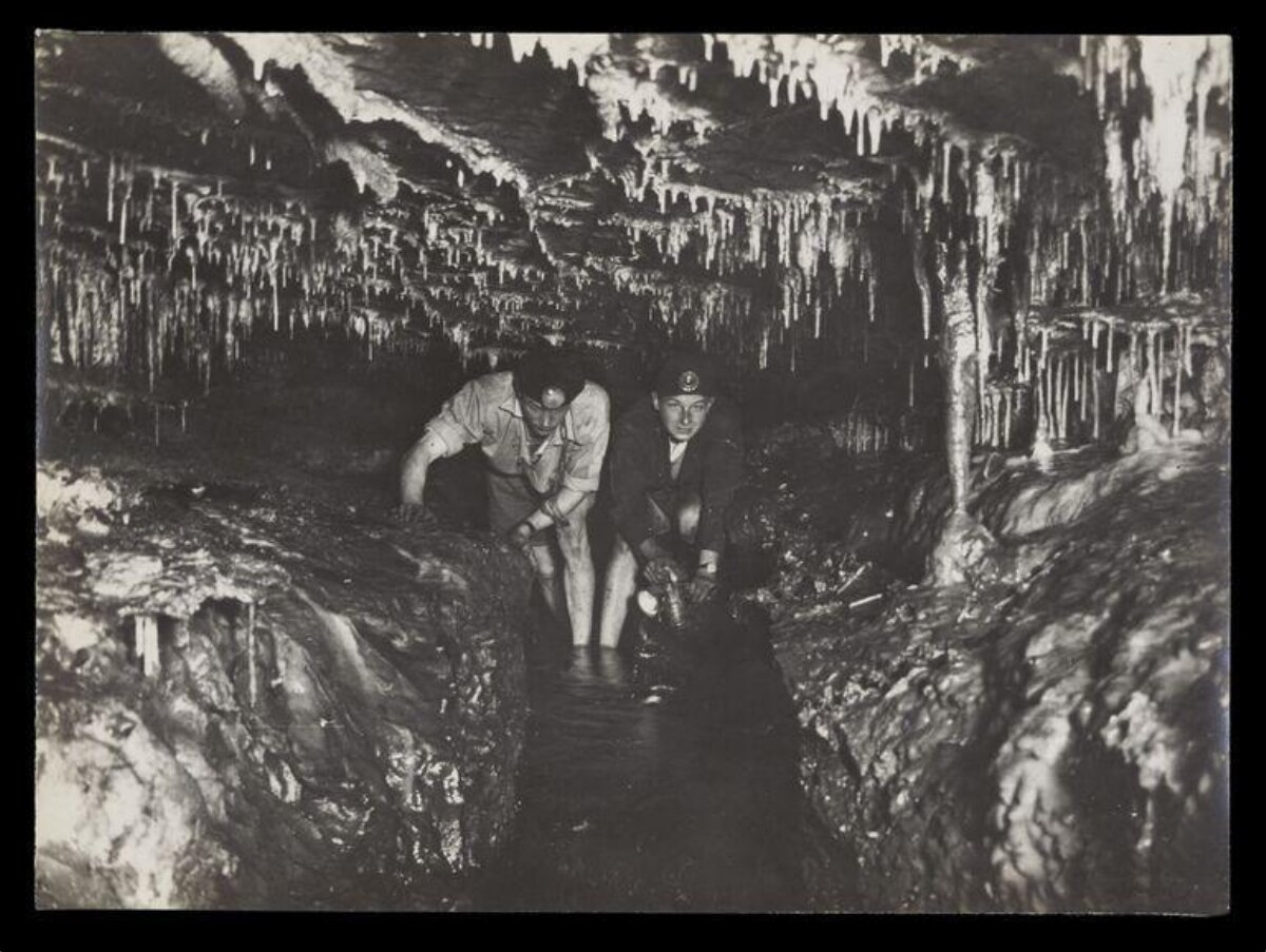 Two Cavers Exploring Water-Filled Cave