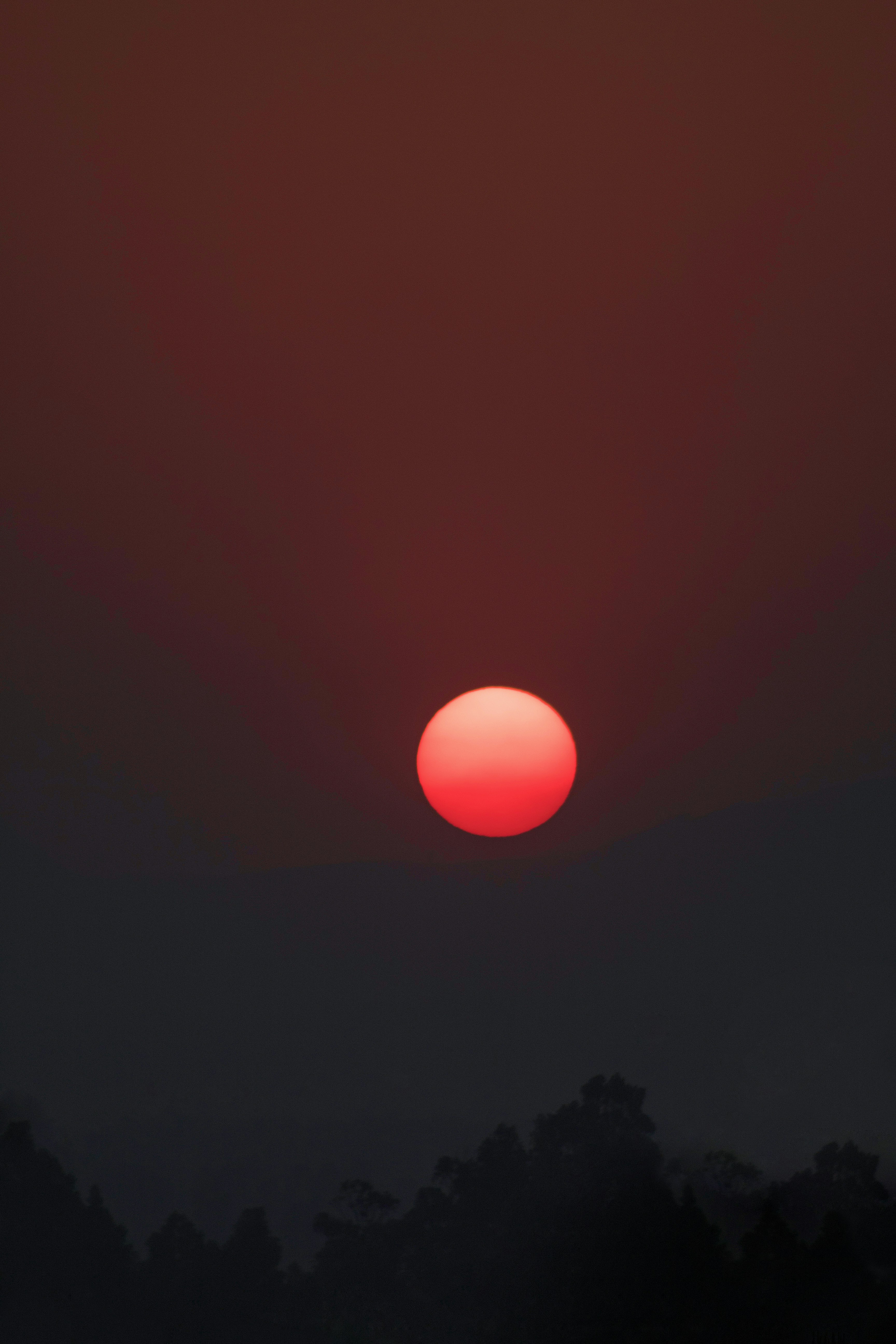 Red Sun Setting Over Forested Hills