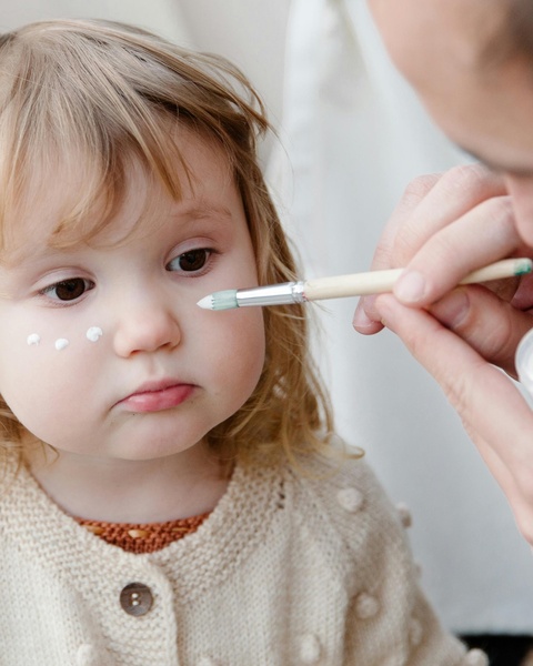 Adult Applying Face Paint to Toddler