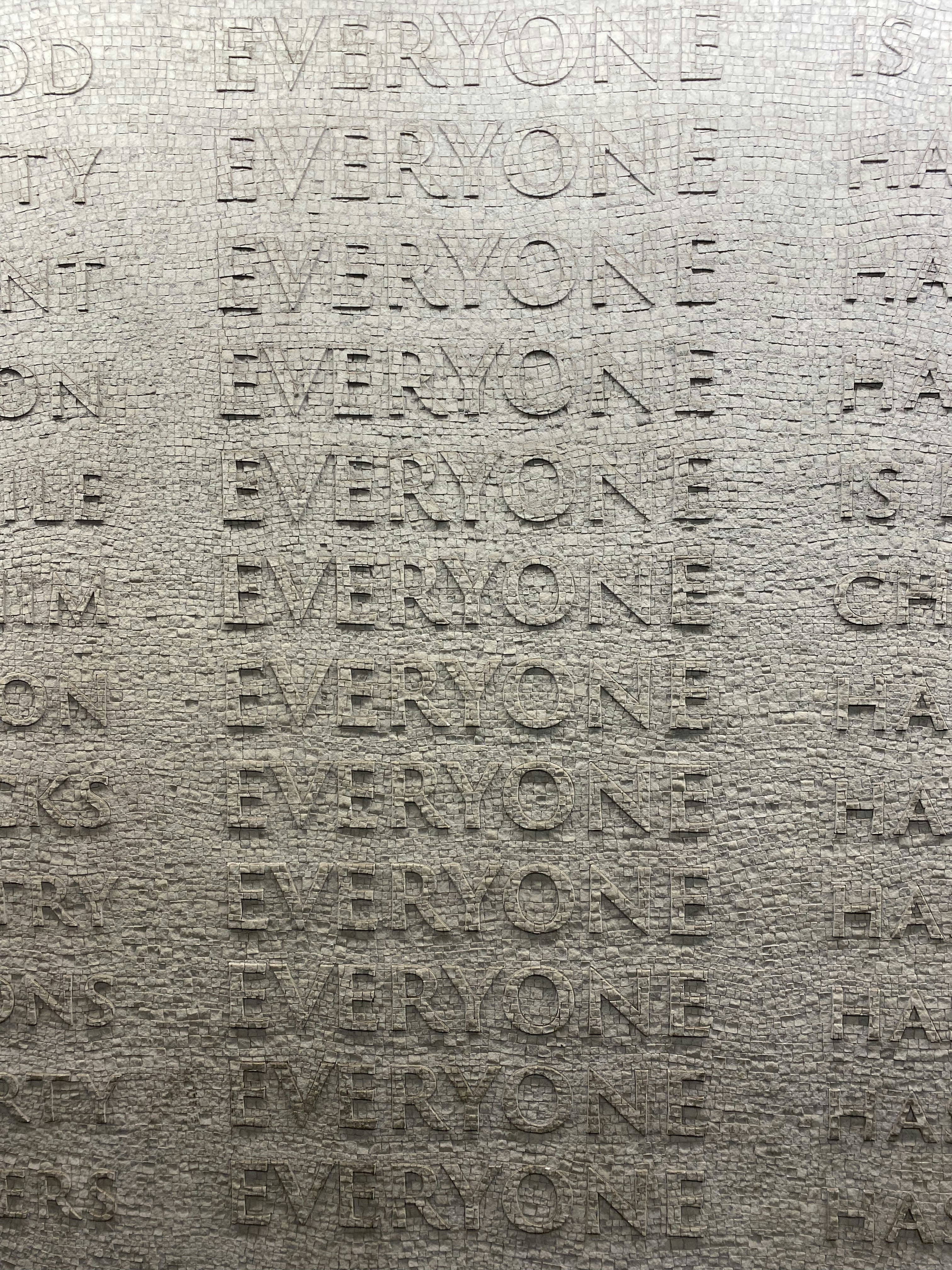 Repeated EVERYONE Text on Stone Wall