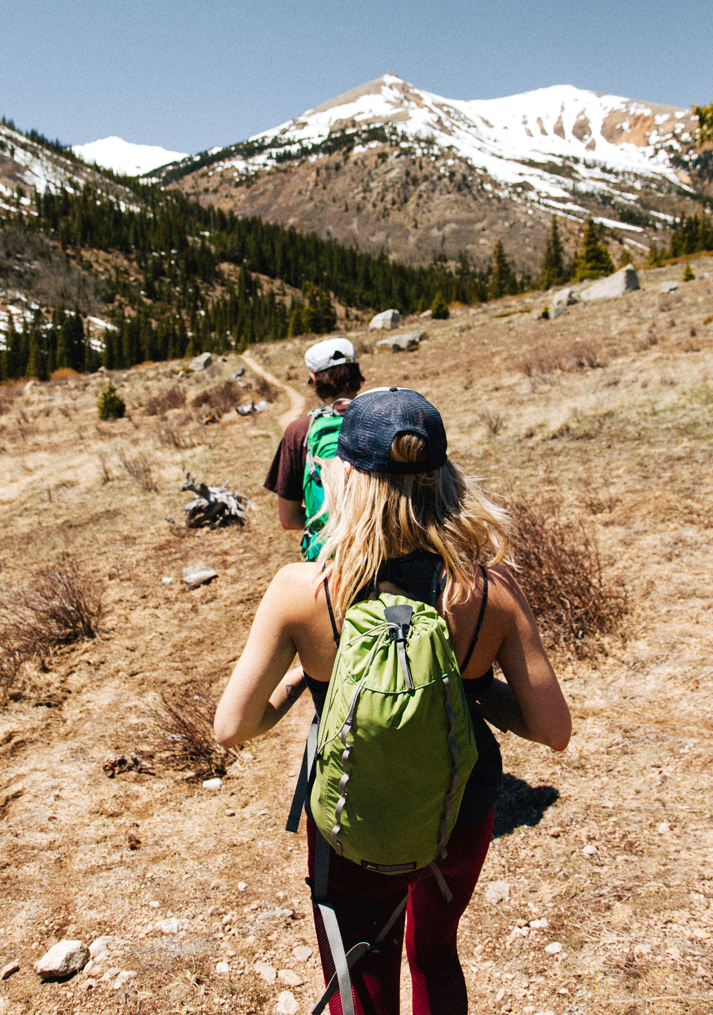 Two Hikers Hiking Toward Snowy Mountains
