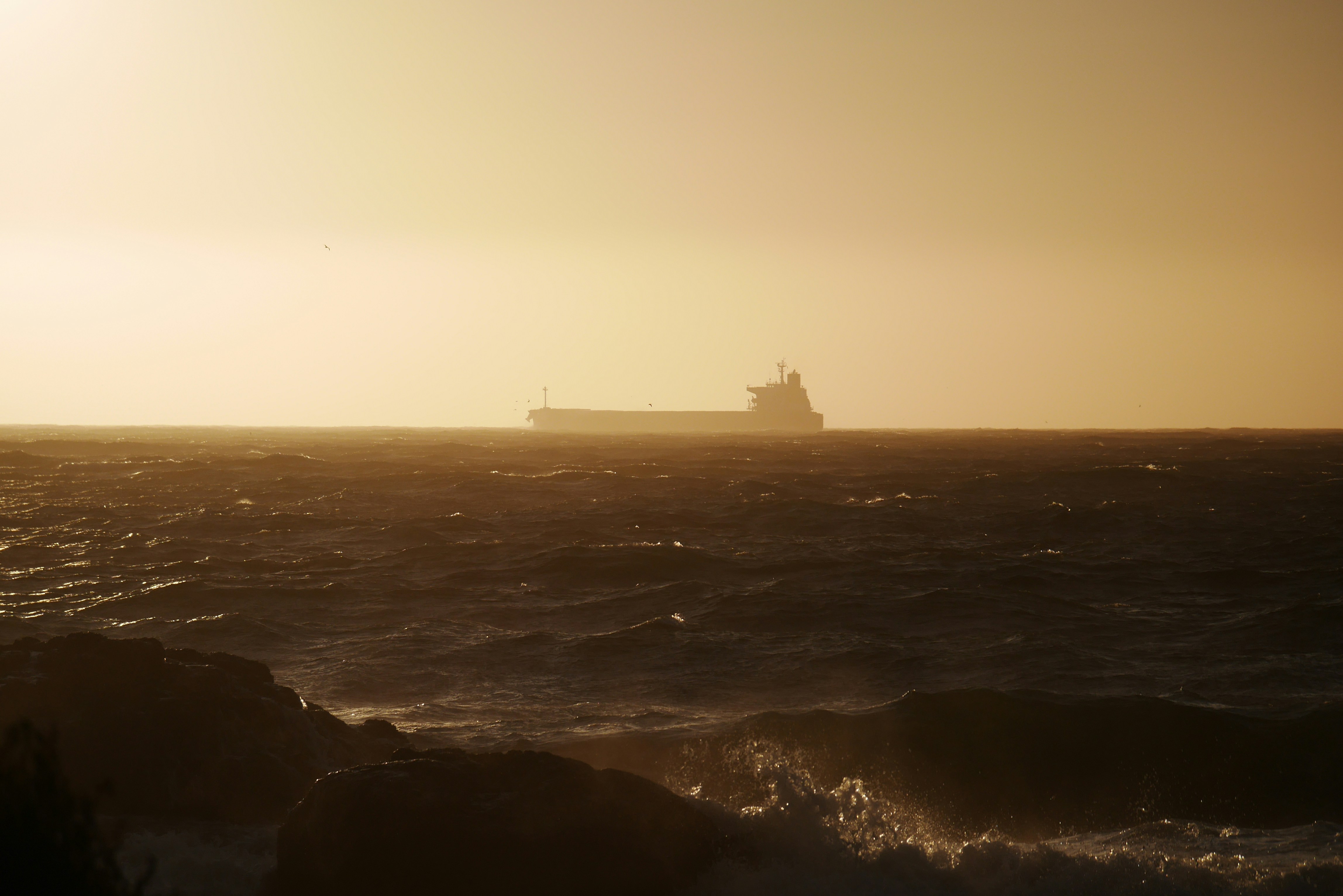 Cargo Ship on Wavy Sea at Sunset