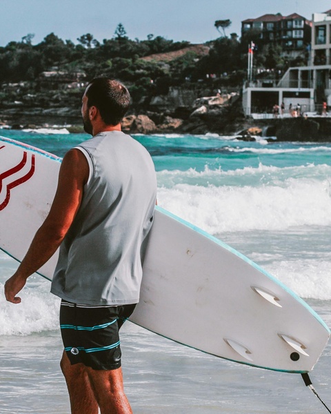 Surfer Carrying Surfboard Into Ocean