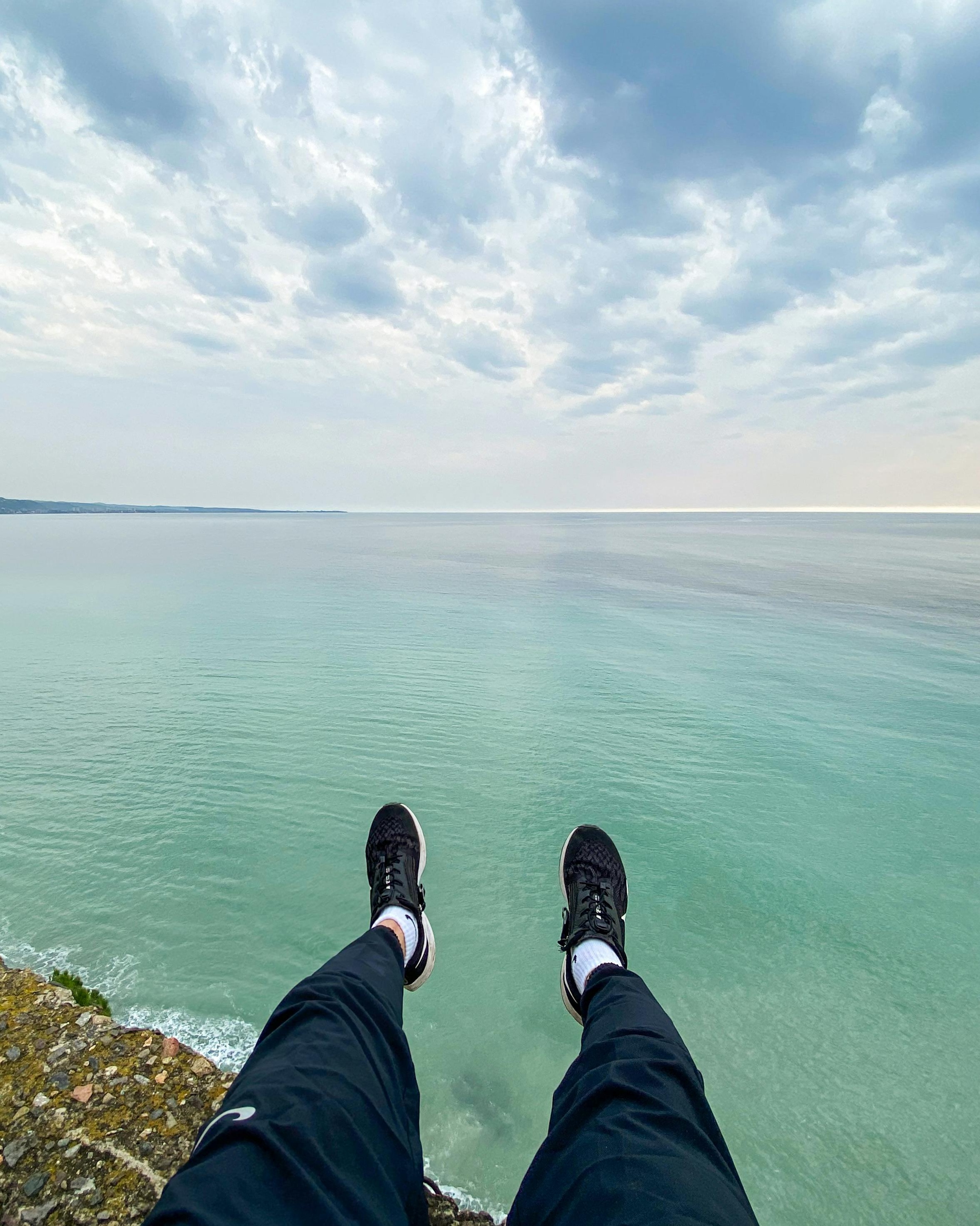 Legs Dangling Over Sea Cliff Edge