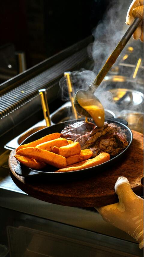 Pouring Gravy Over Hot Steak and Fries