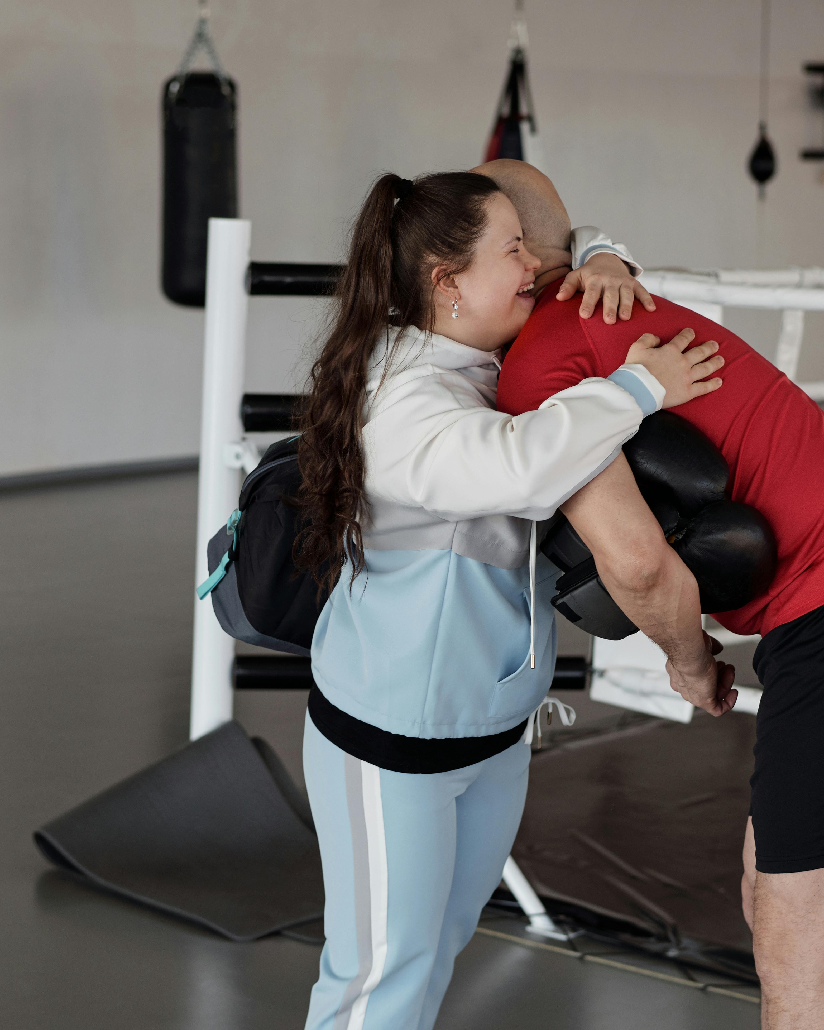 Woman Hugs Boxing Trainer In Gym