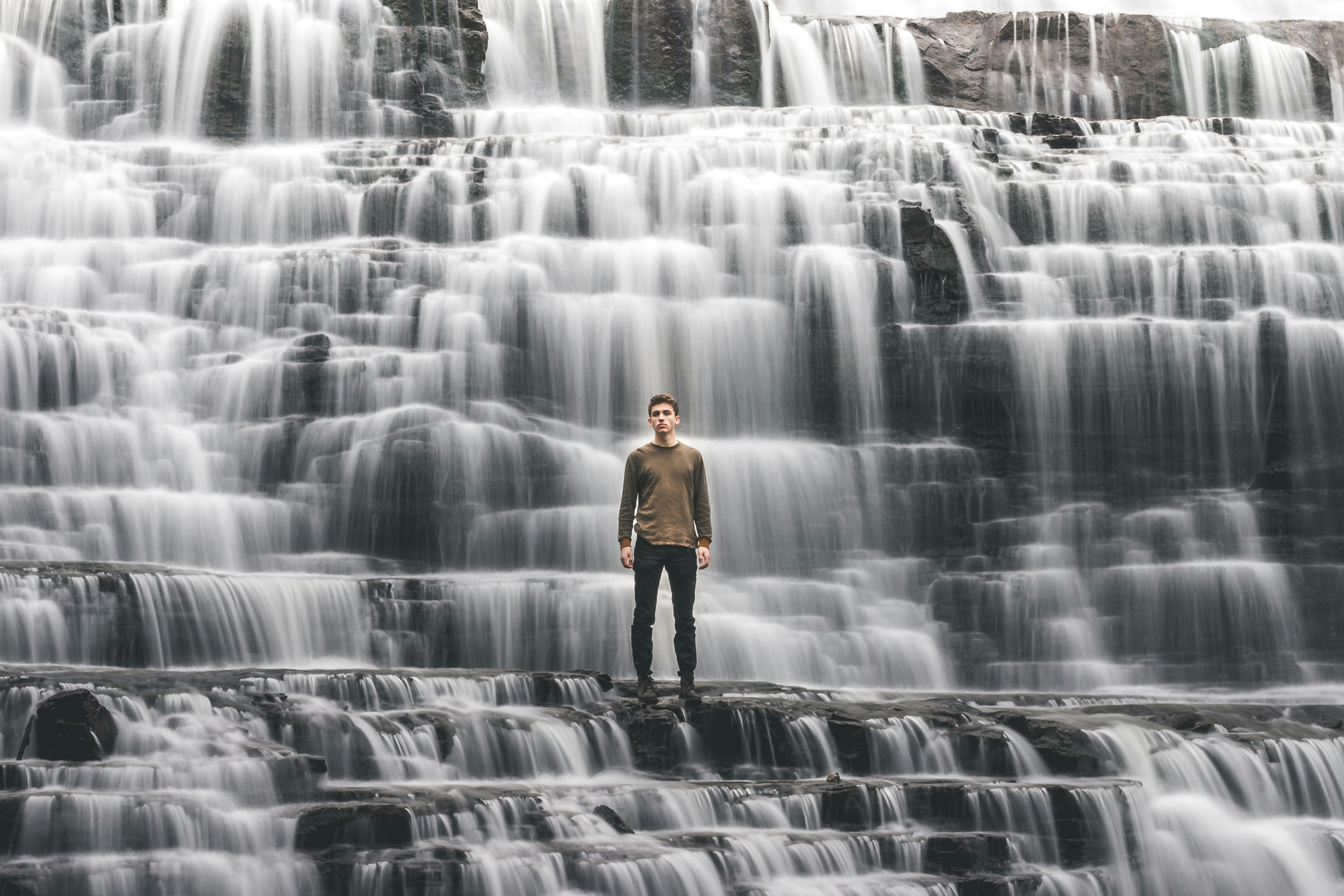 Man Standing Before Layered Waterfall