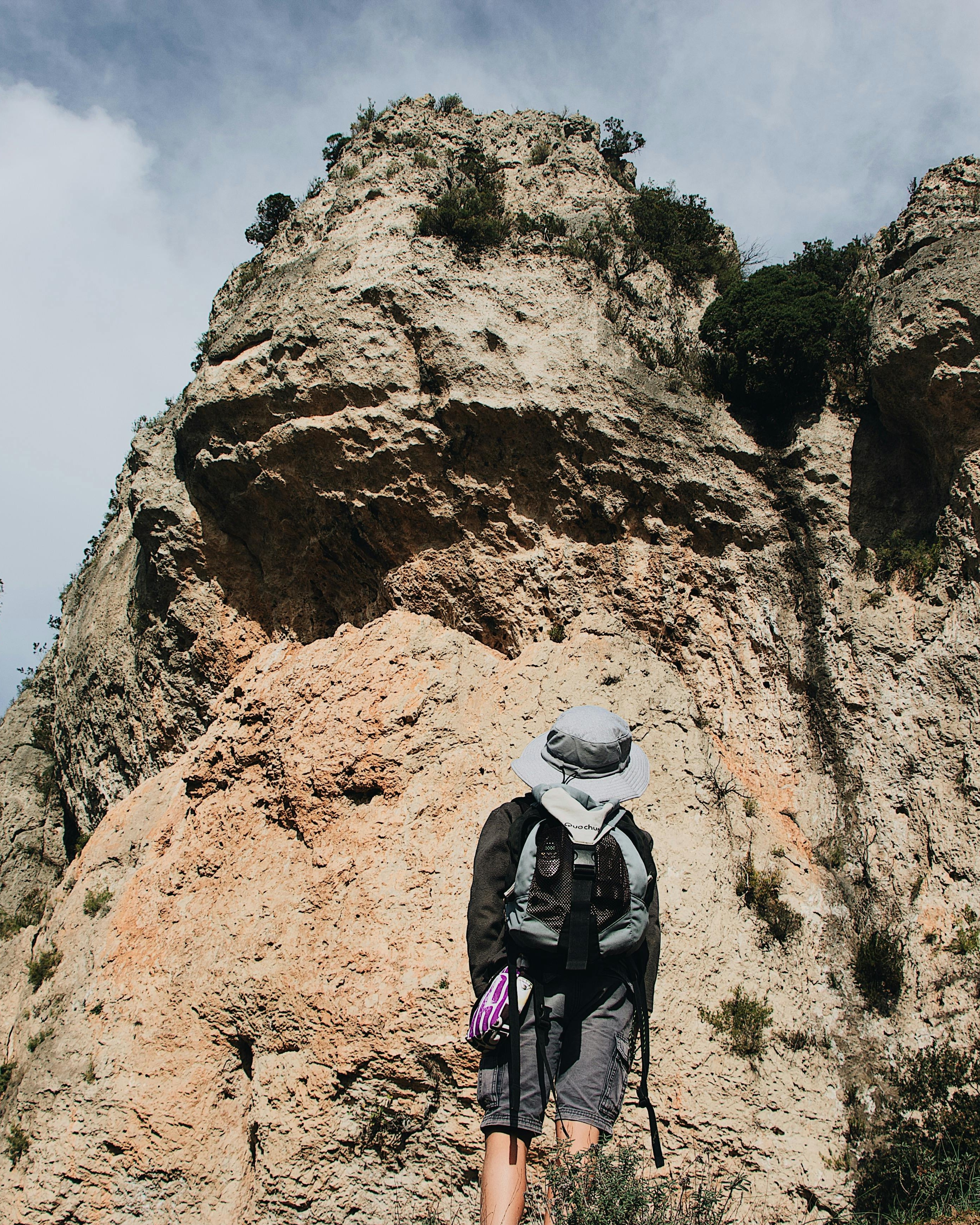 Hiker Facing Steep Rock Cliff