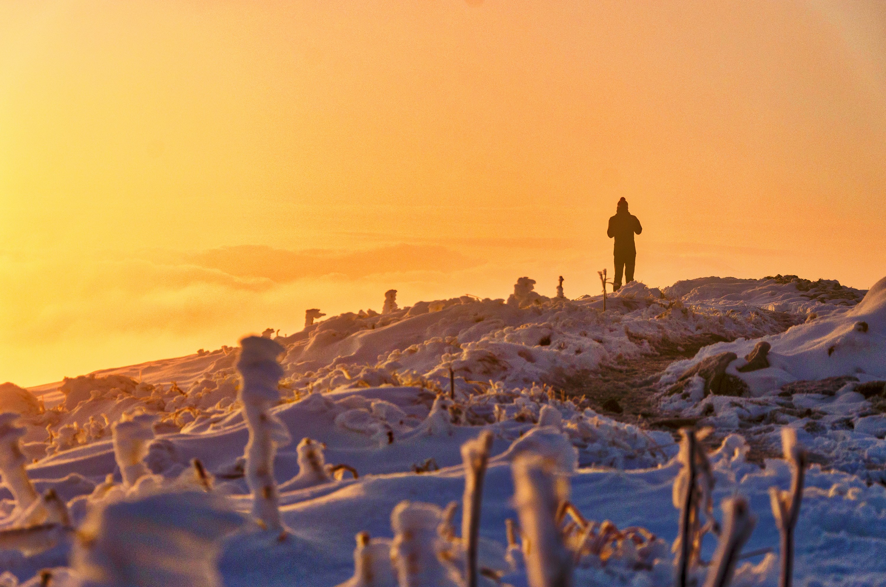Hiker on Snowy Hill at Sunset