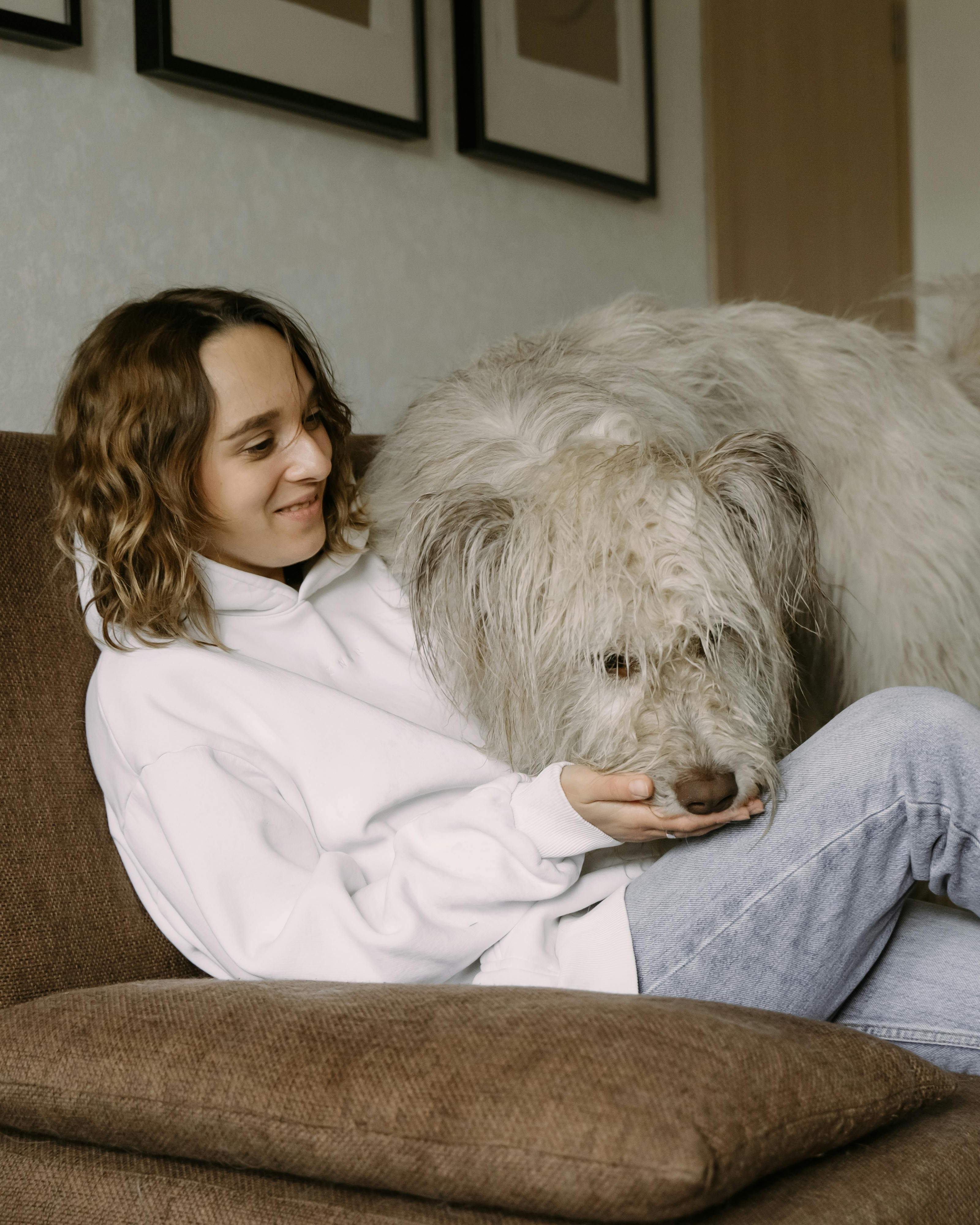 Woman Cuddling Fluffy Dog On Couch