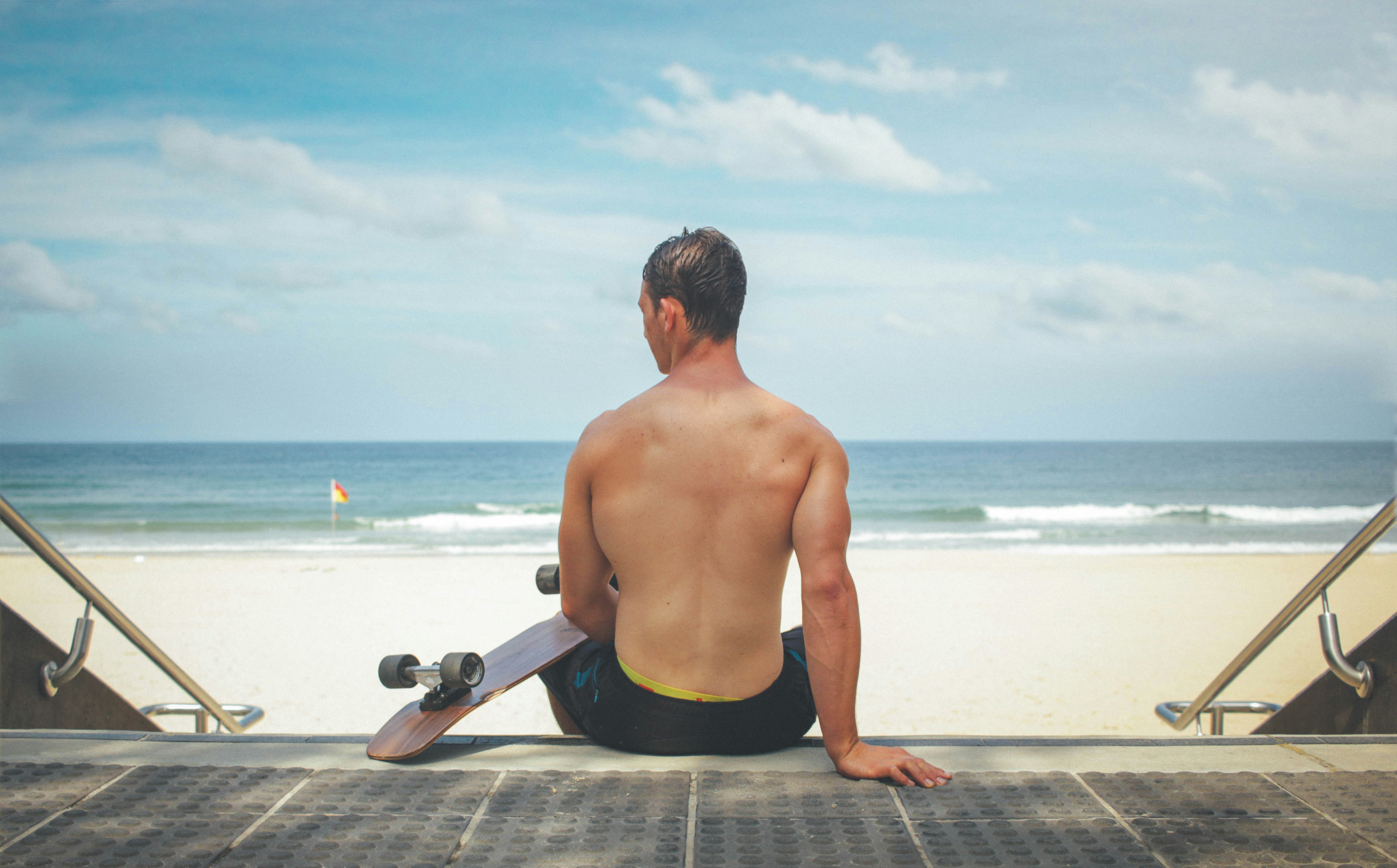 Shirtless Man With Longboard at Beach