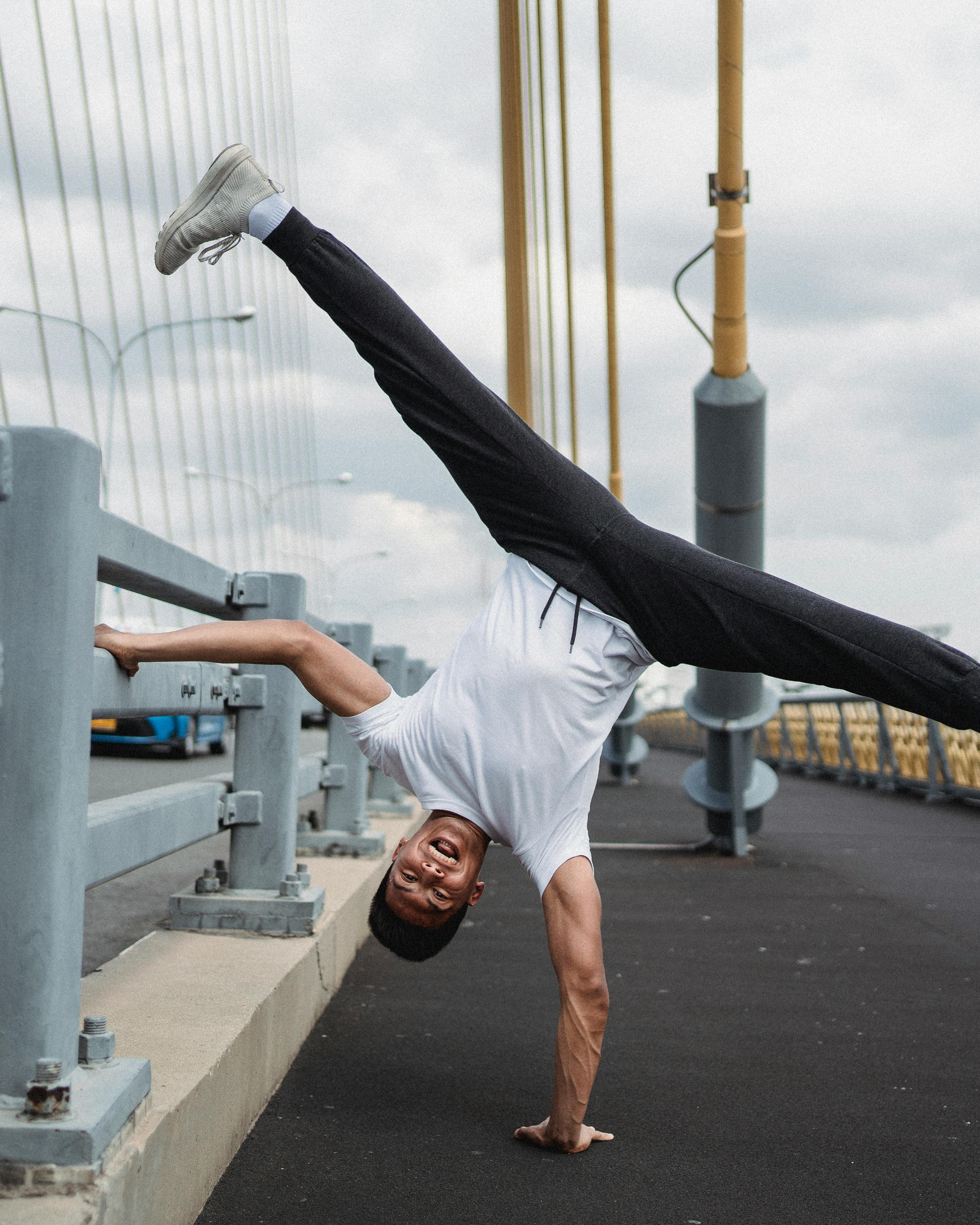 Man Doing Handstand Split On Bridge