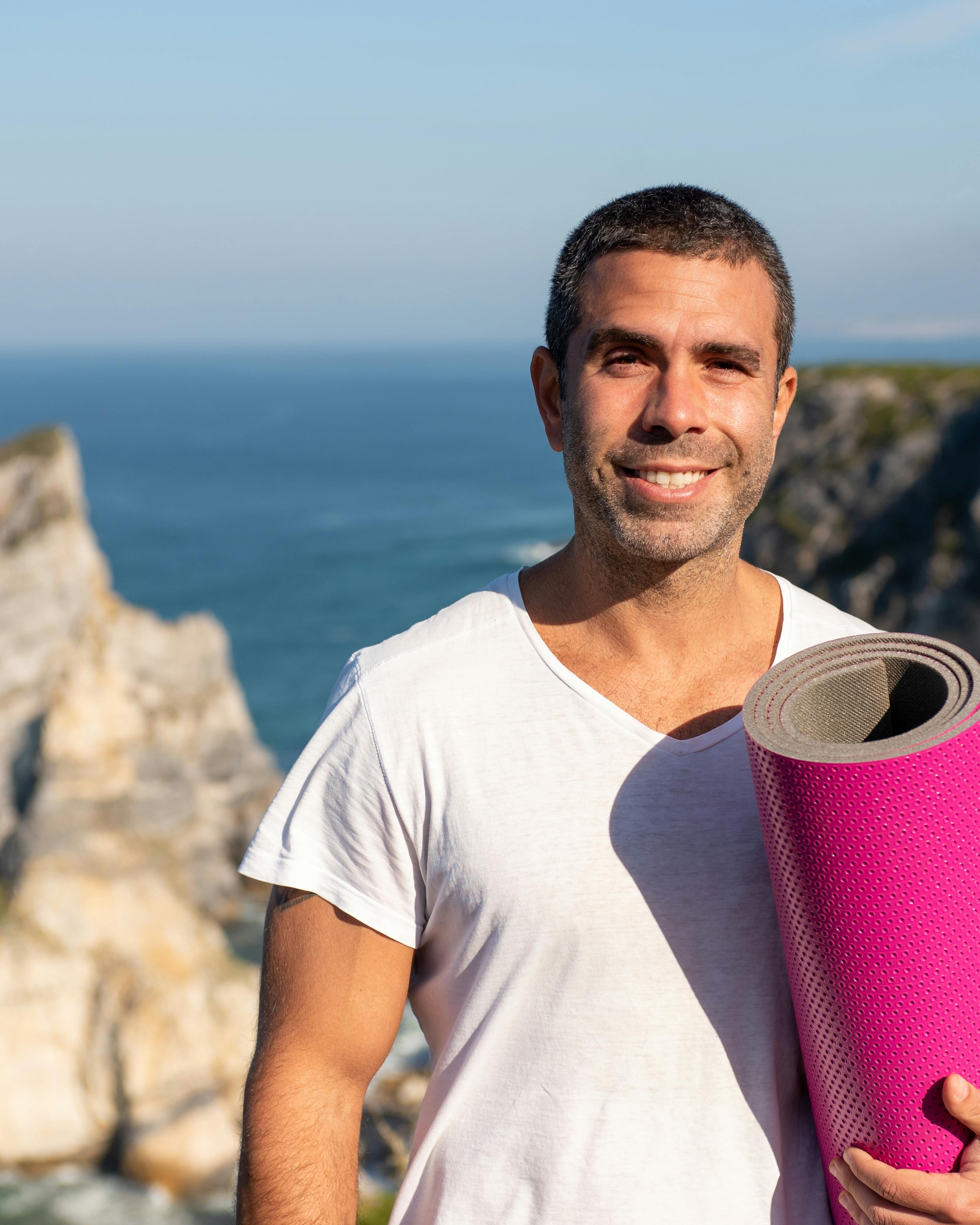Man Holding Yoga Mat By Coastal Cliffs