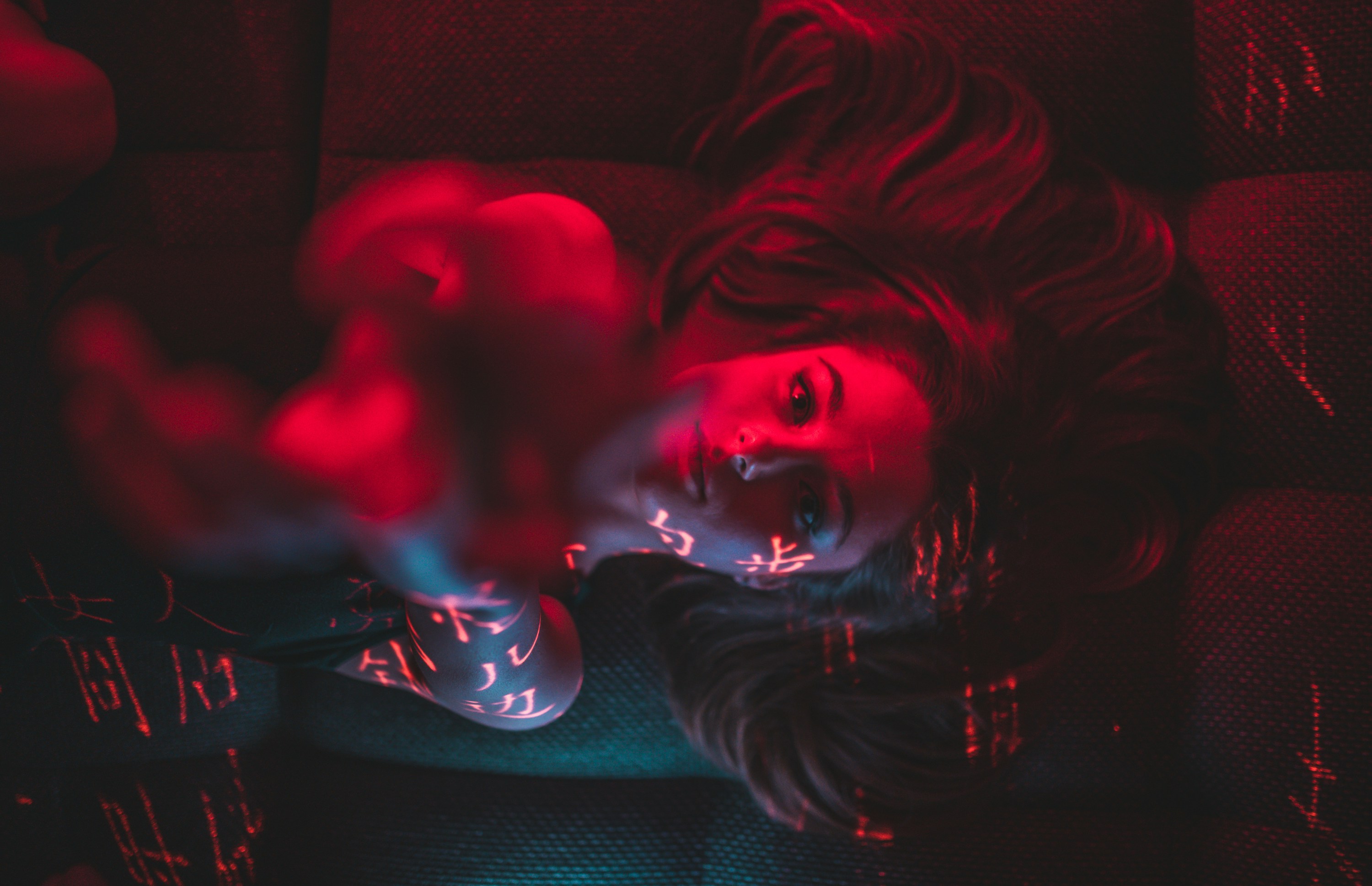 Woman Lying With Projected Text Under Red Light