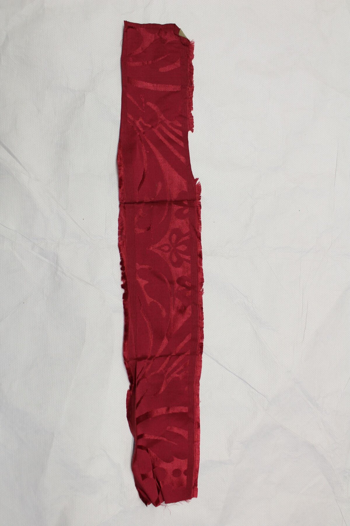 Red patterned fabric strip on white background