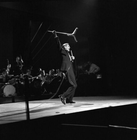 Male Singer Performing on Stage With Band