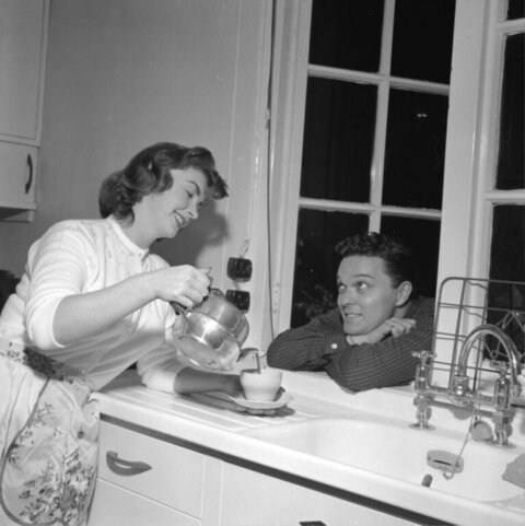 Woman Pouring Tea for Man in Kitchen