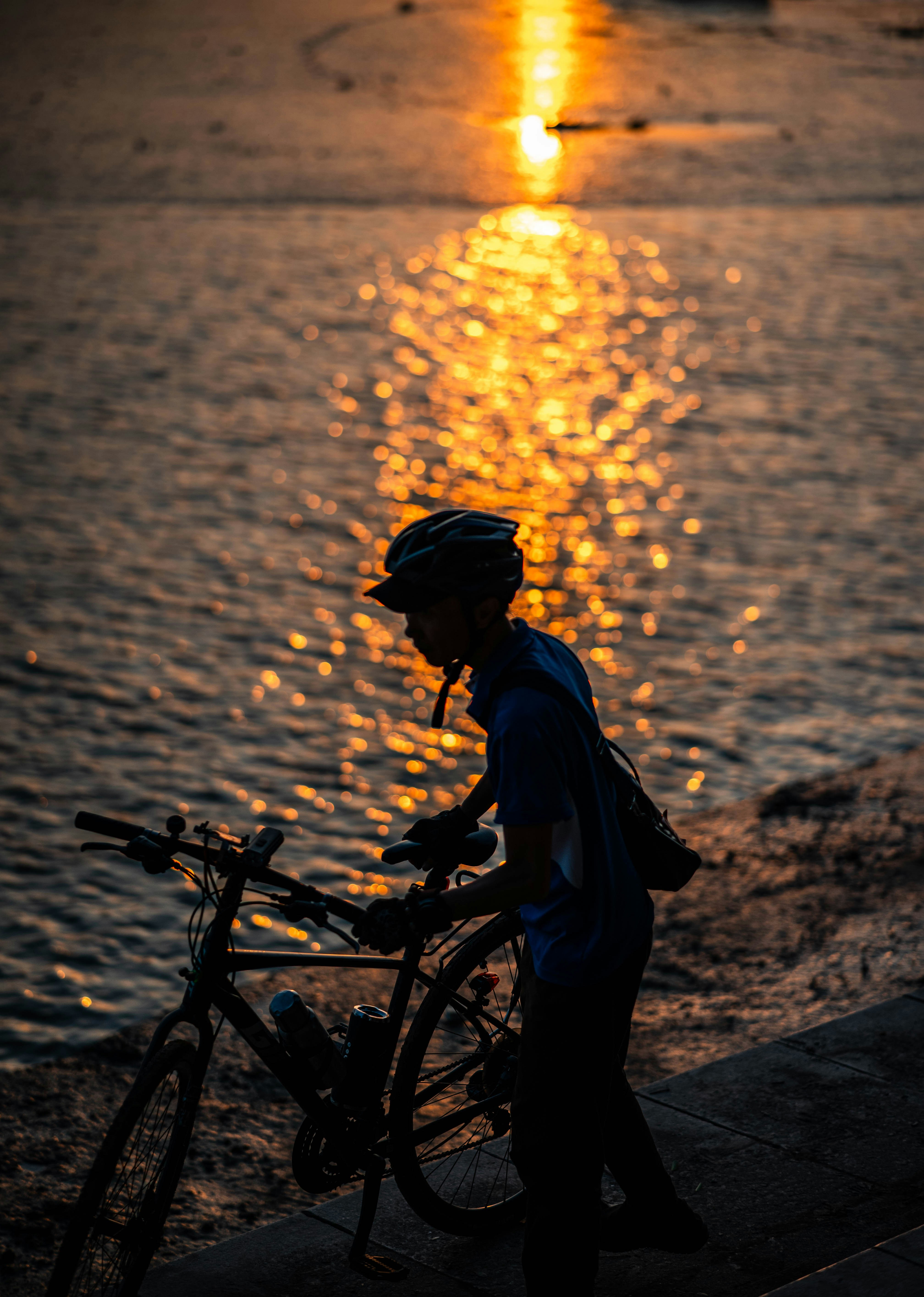 Cyclist By Water At Golden Sunset
