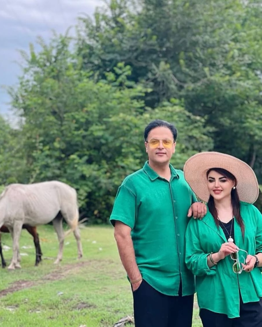 Couple Posing in Grassy Pasture With Horse