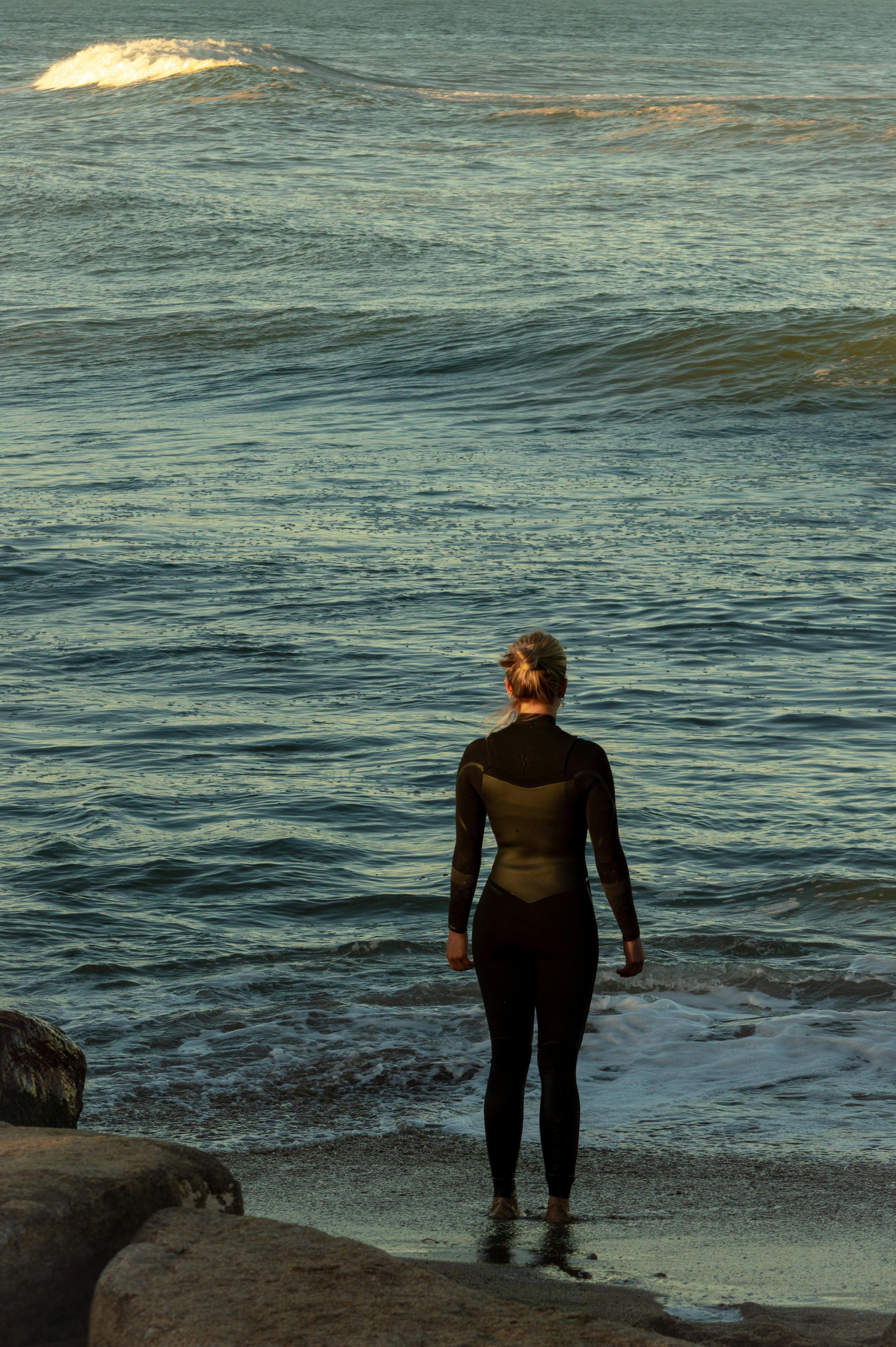 Surfer Watching Ocean from Sandy Shore