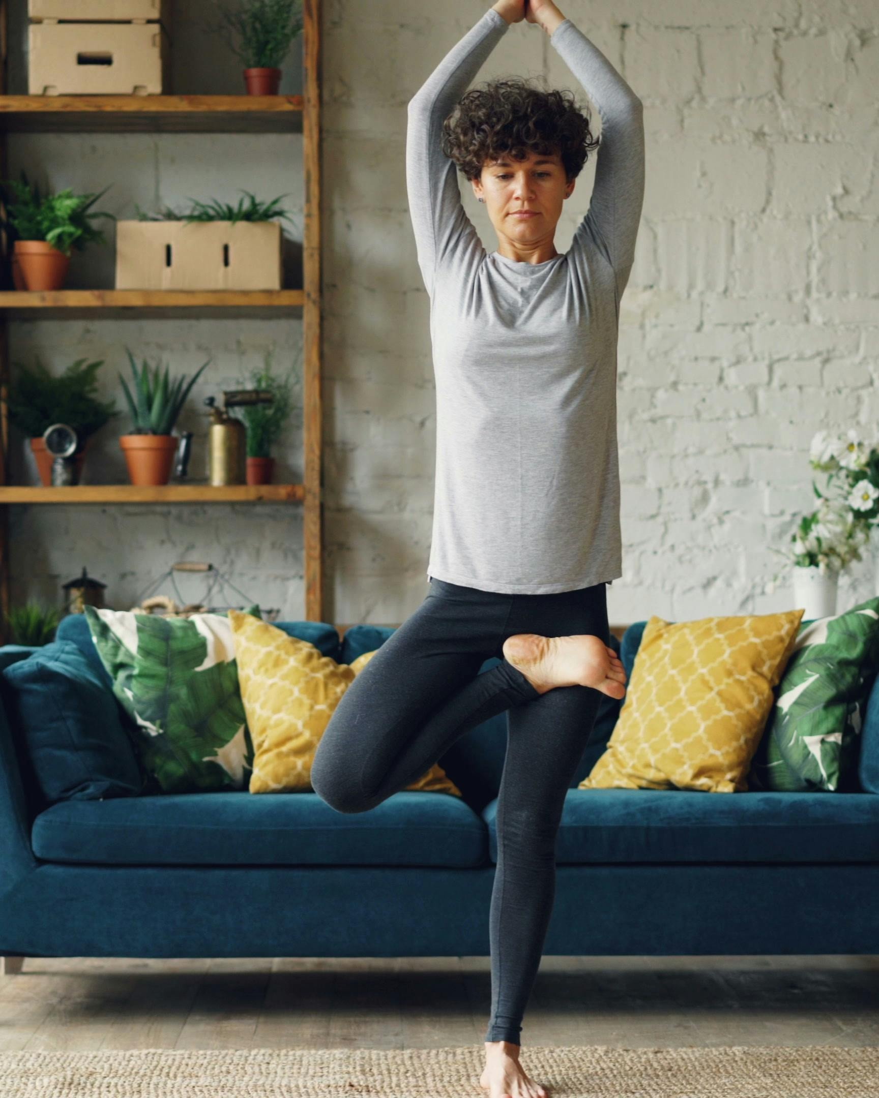 Woman Practicing Tree Pose Yoga At Home