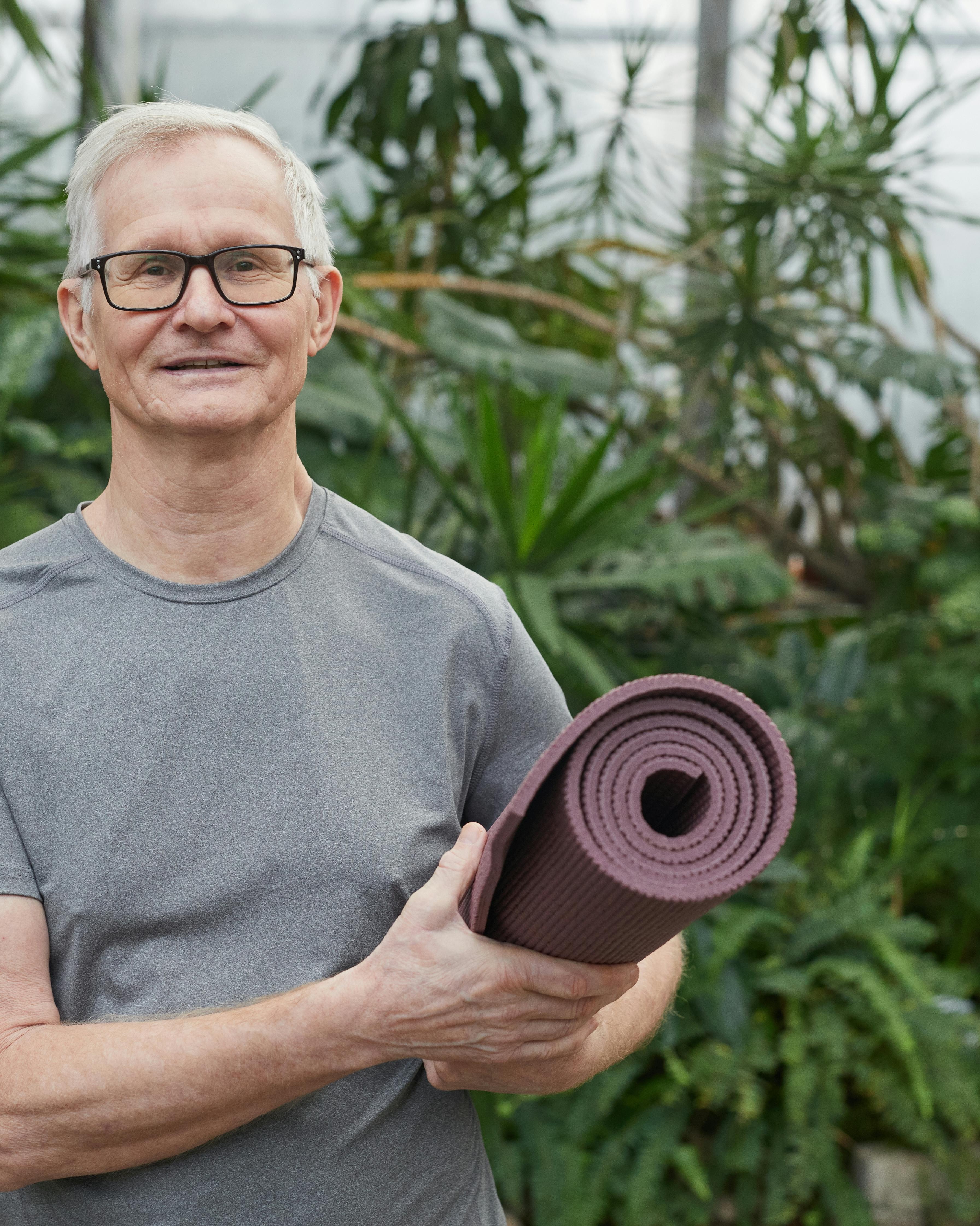 Senior Man Holding Rolled Yoga Mat