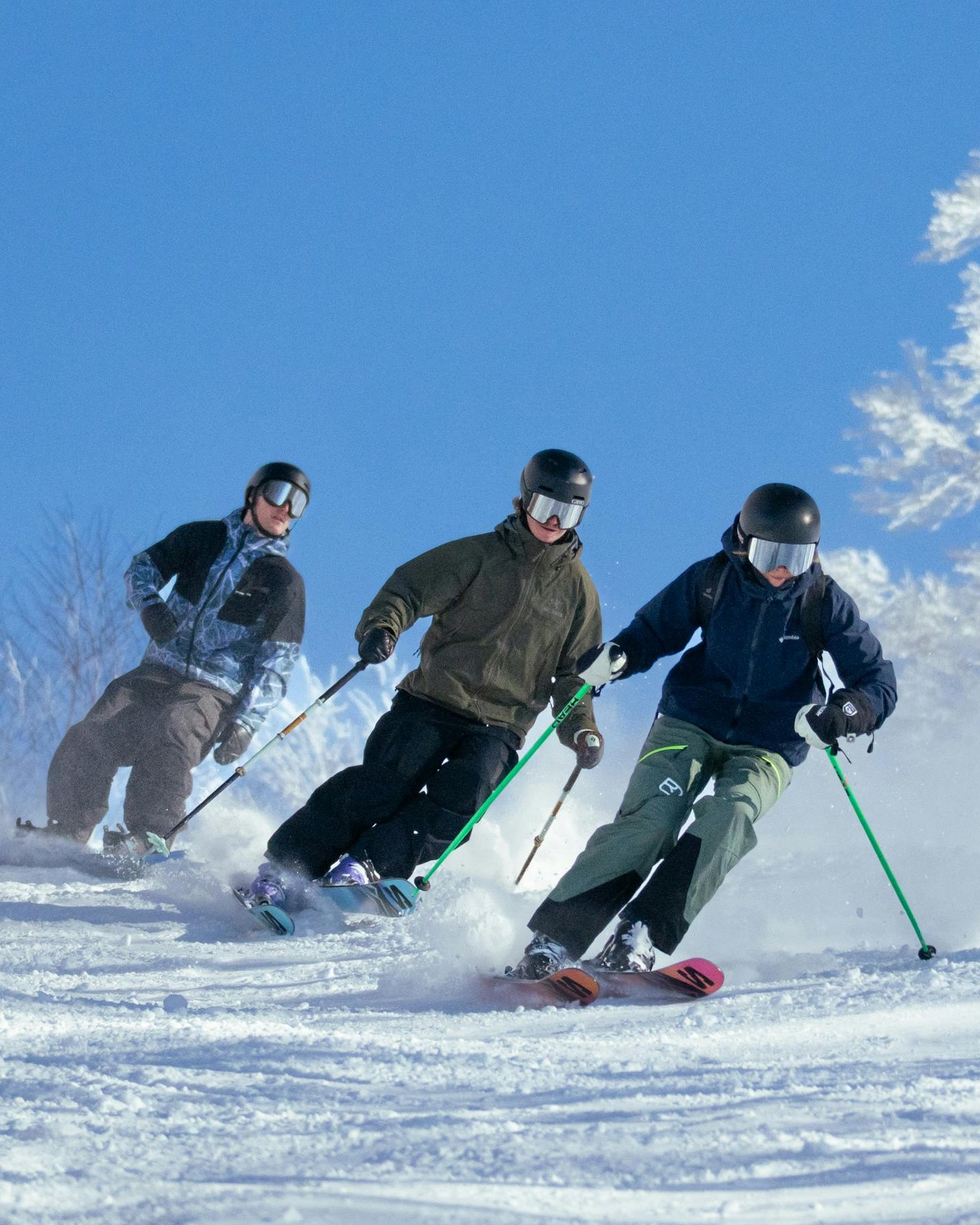 Three Skiers Skiing Downhill