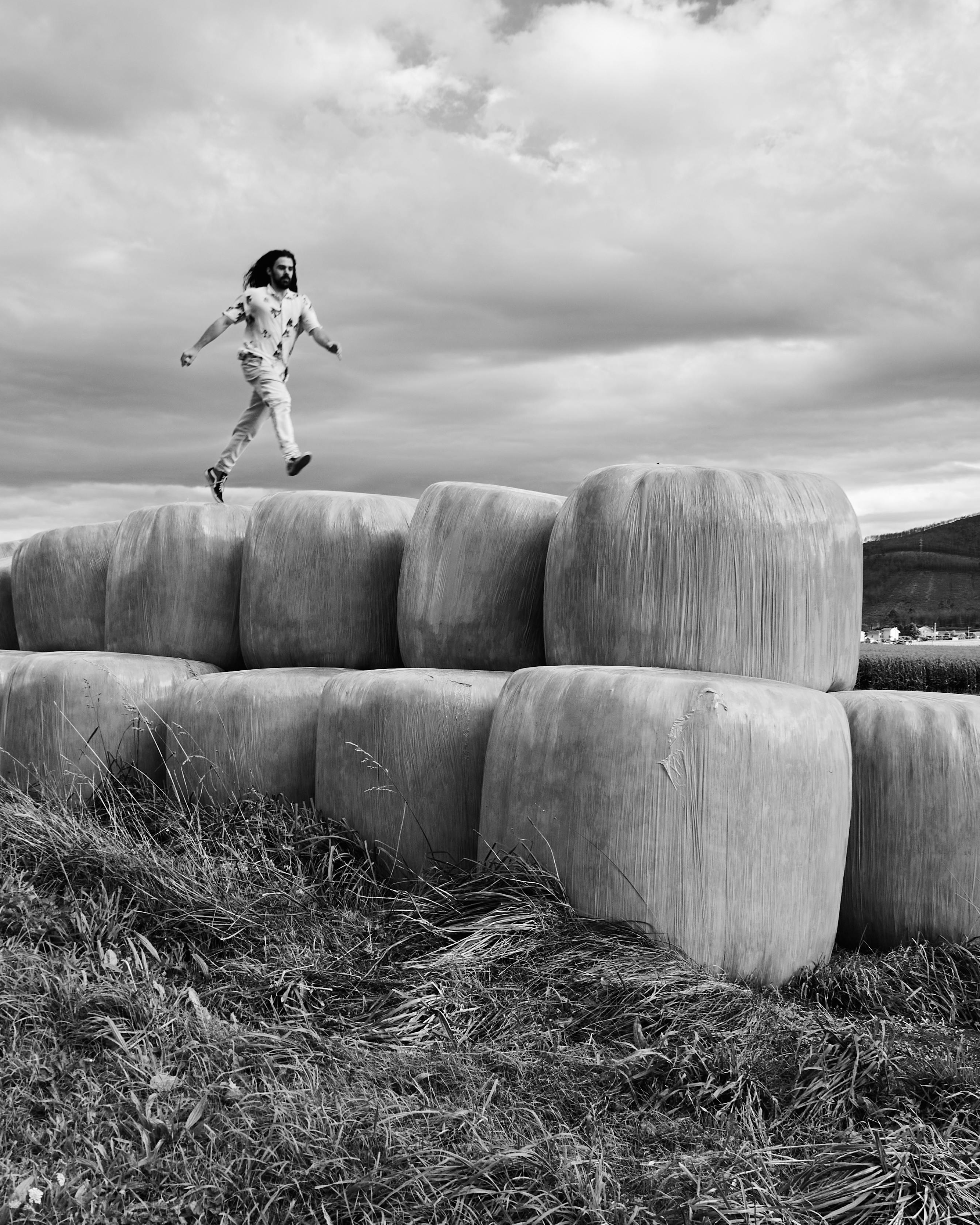 Man Jumping Across Stacked Hay Bales