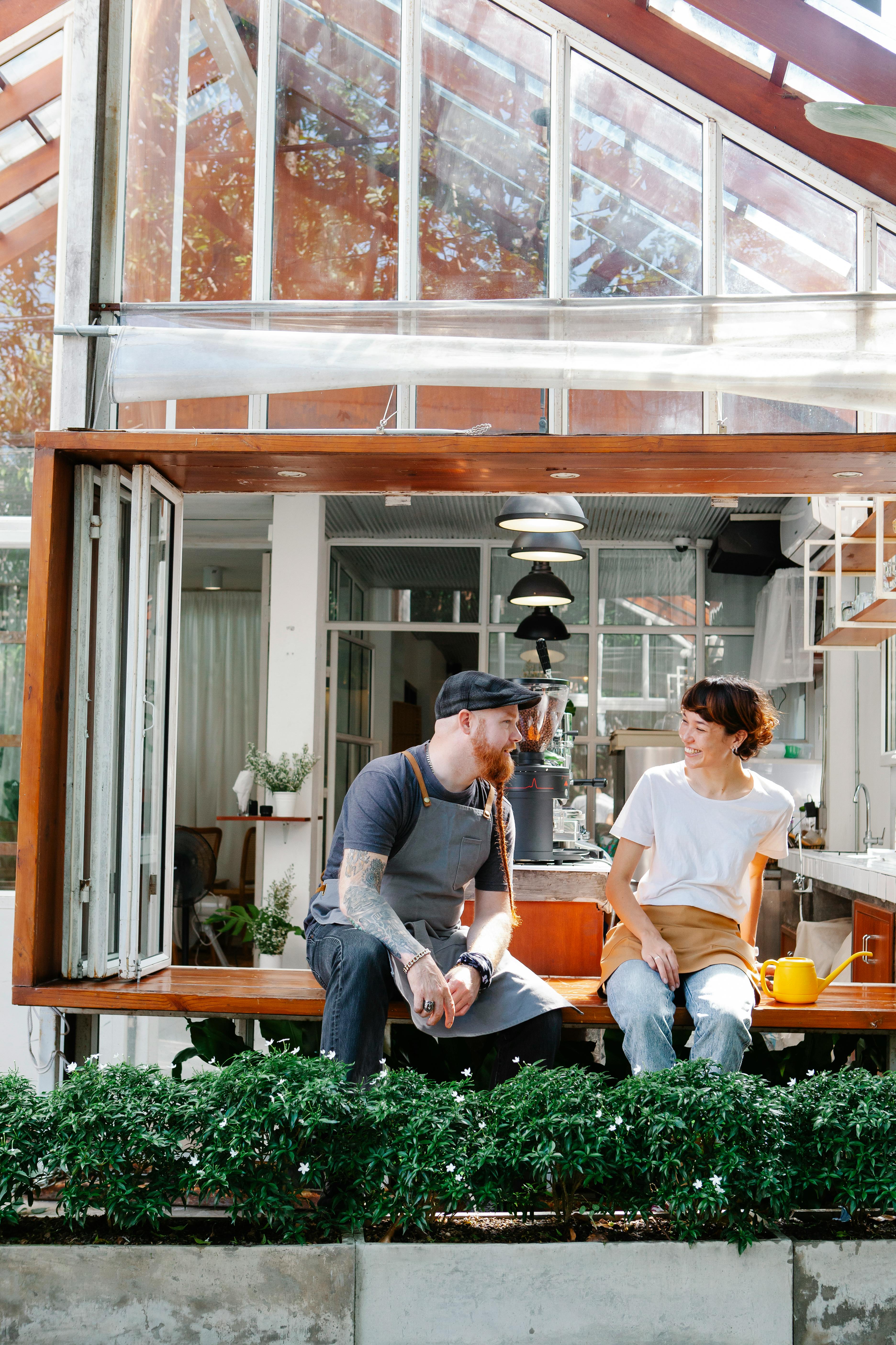 Two Baristas Chatting at Sunlit Coffee Shop