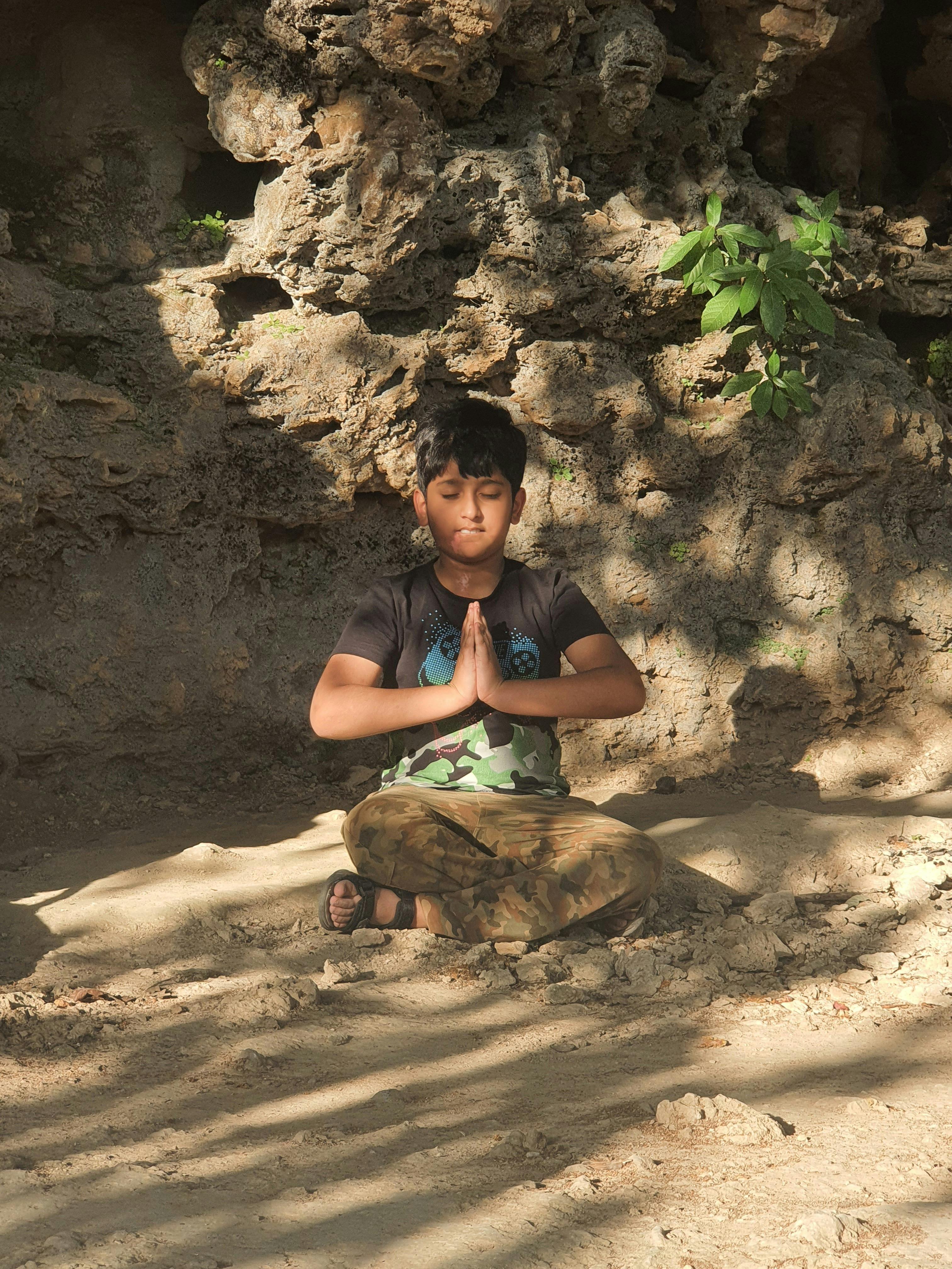 Boy Meditating by Rocky Cave Wall — Fitness