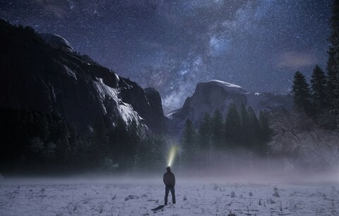 Hiker Watching Starry Sky Over Snowy Mountains