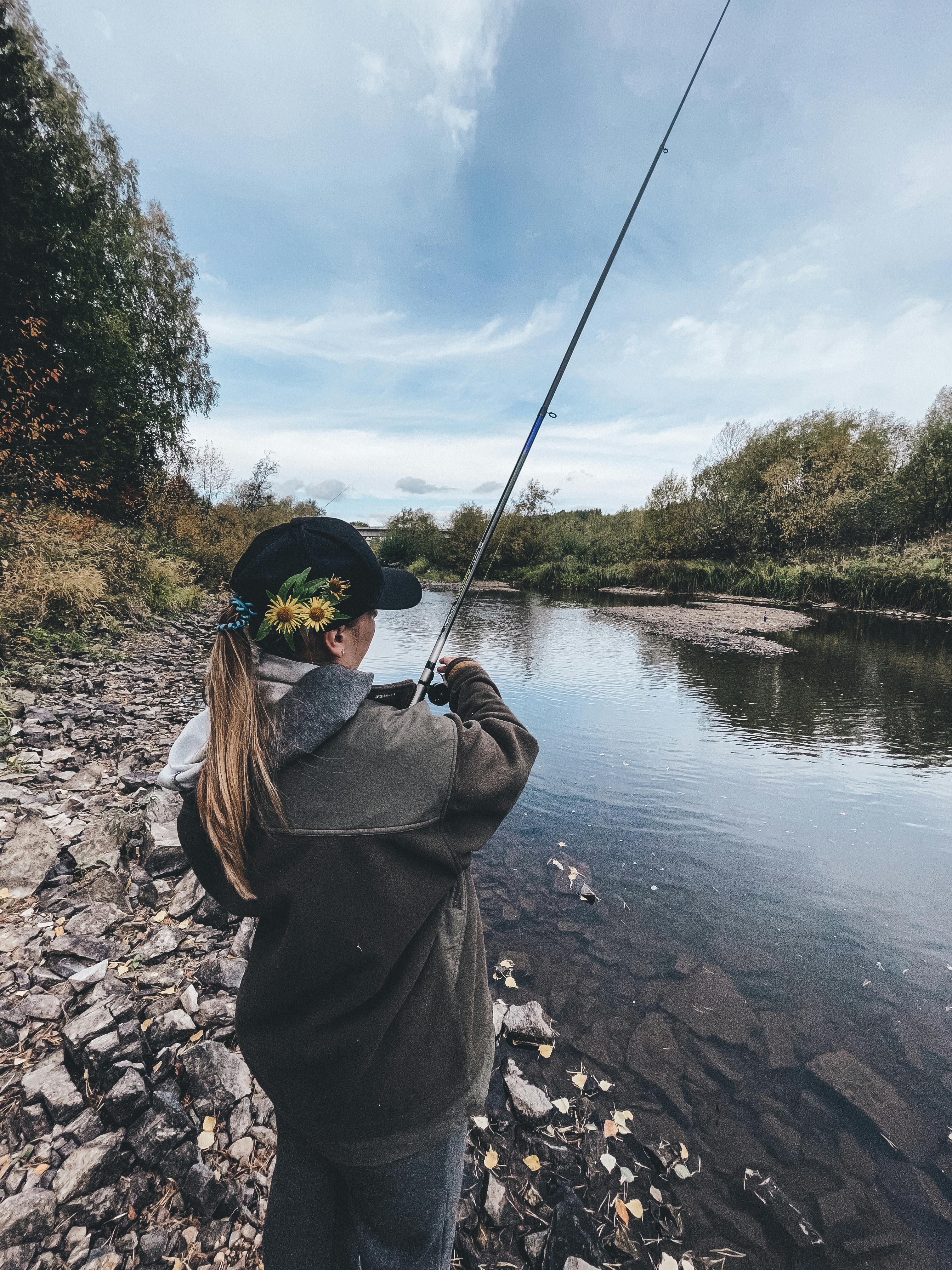 Woman Fishing By Rocky Riverbank