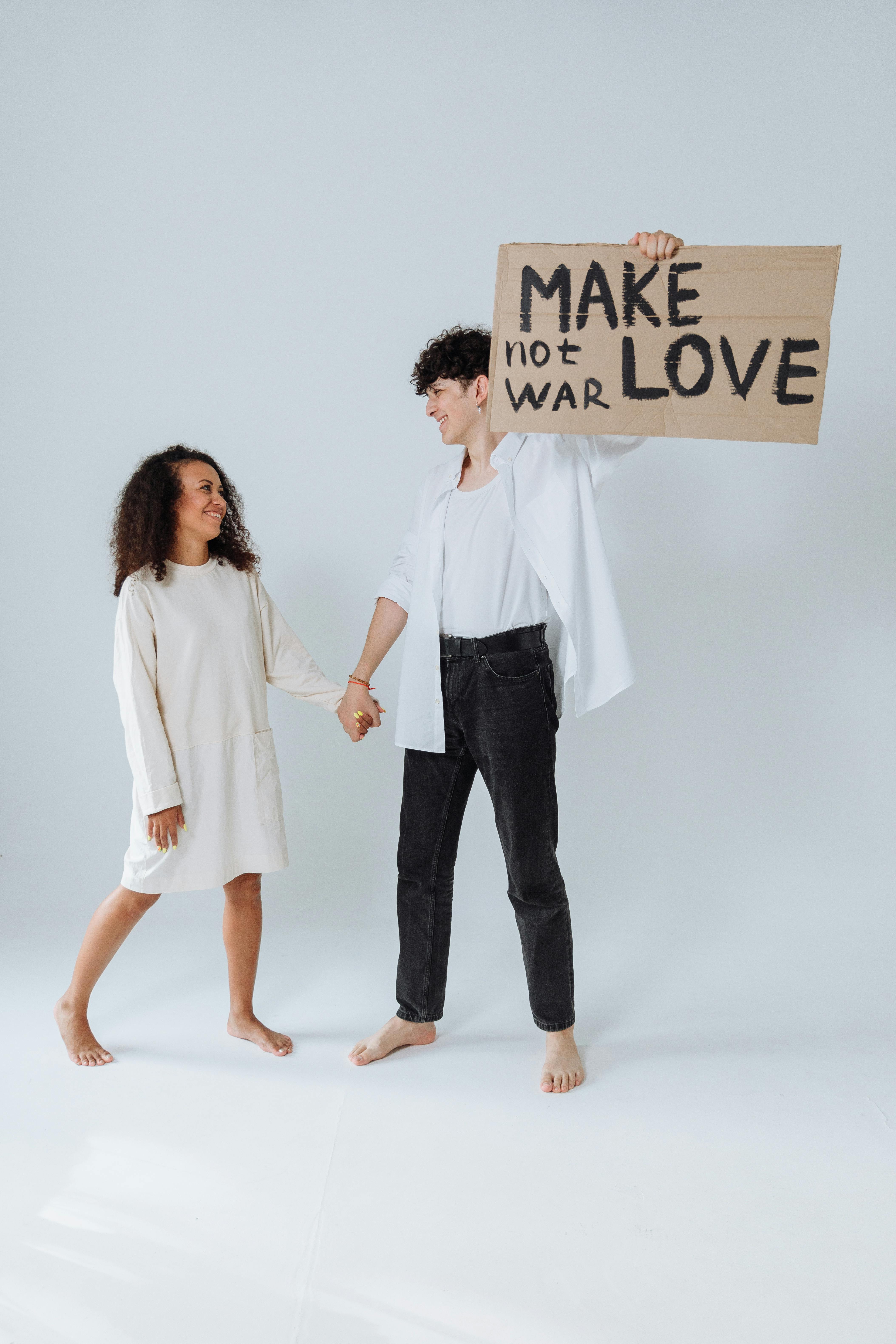 Couple Holding Make Love Not War Sign