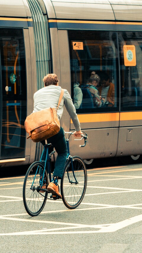 Cyclist Riding Beside City Tram