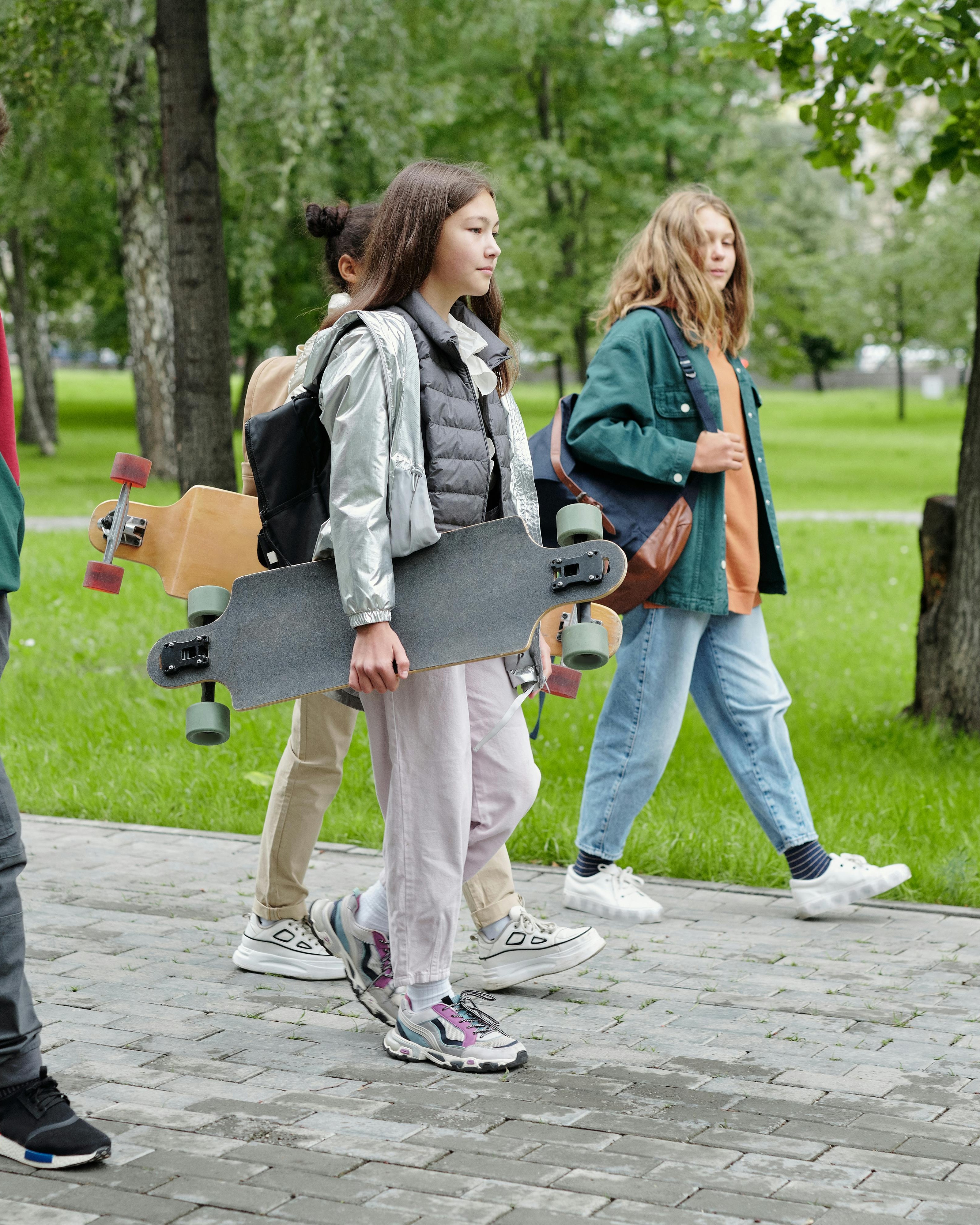 Teens Walking With Longboards in Park
