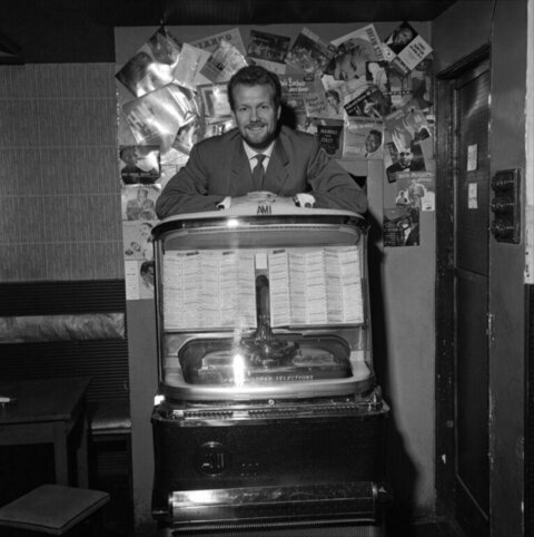 Man Posing Behind Vintage AMI Jukebox