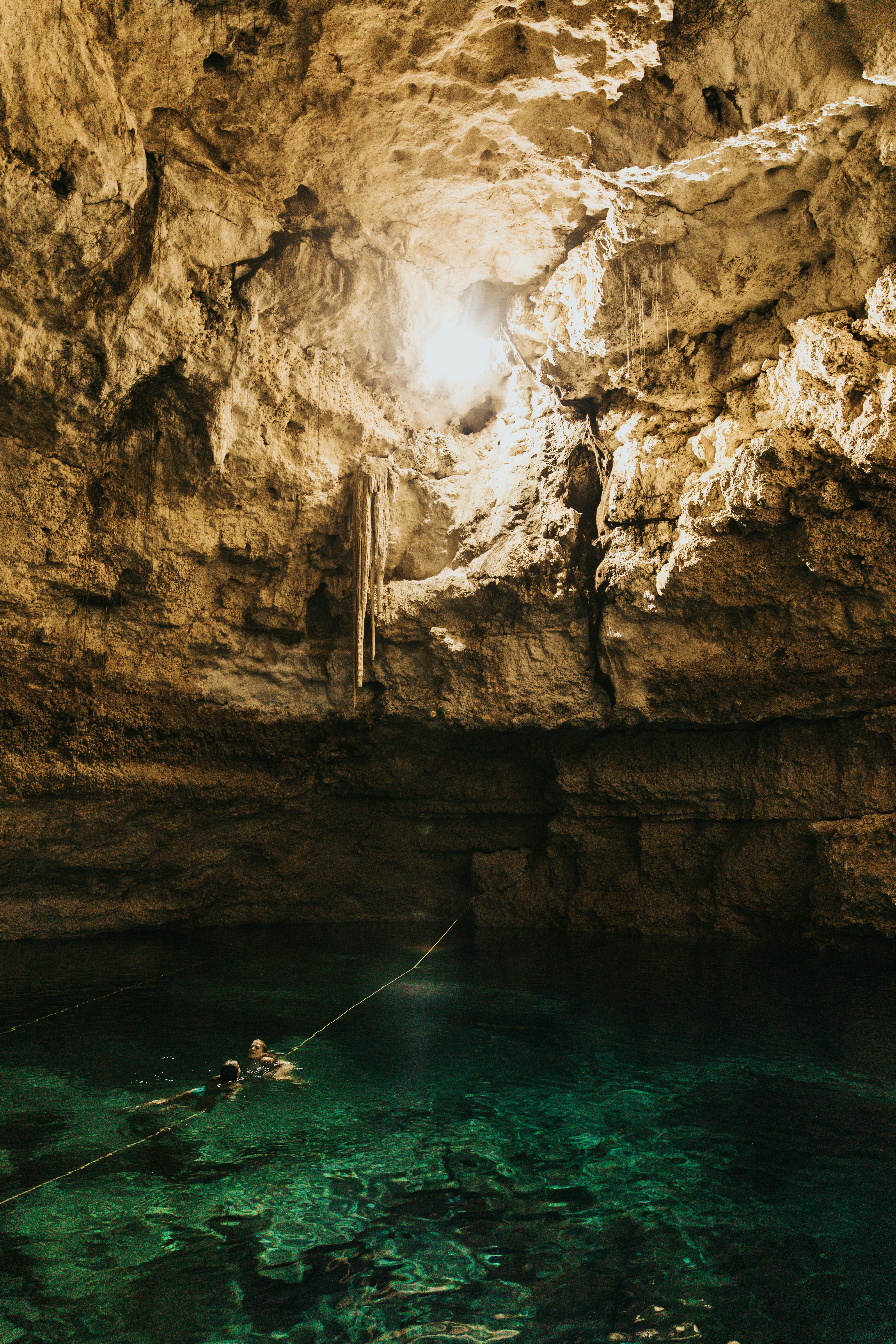 Sunlit Cave Pool With Two Swimmers