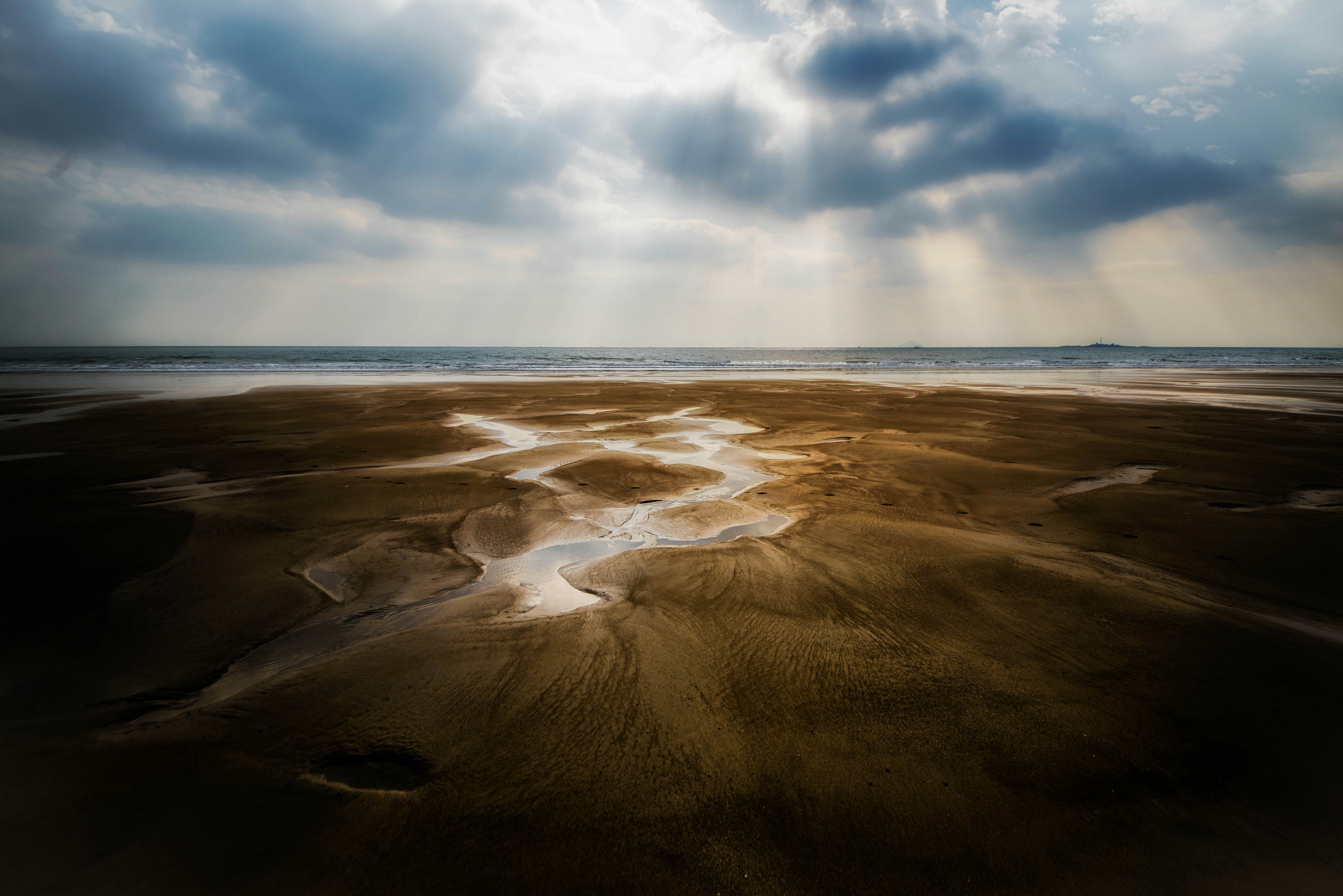 Low Tide Beach with Sunbeams Through Clouds