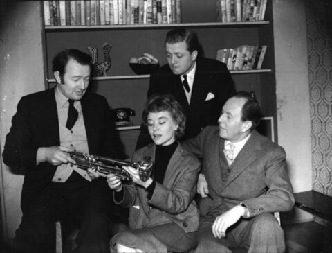 Four People Examining a Trumpet