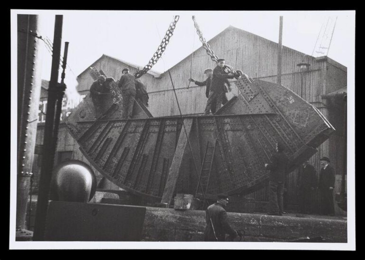 Workers Installing Ship Hull Section at Shipyard