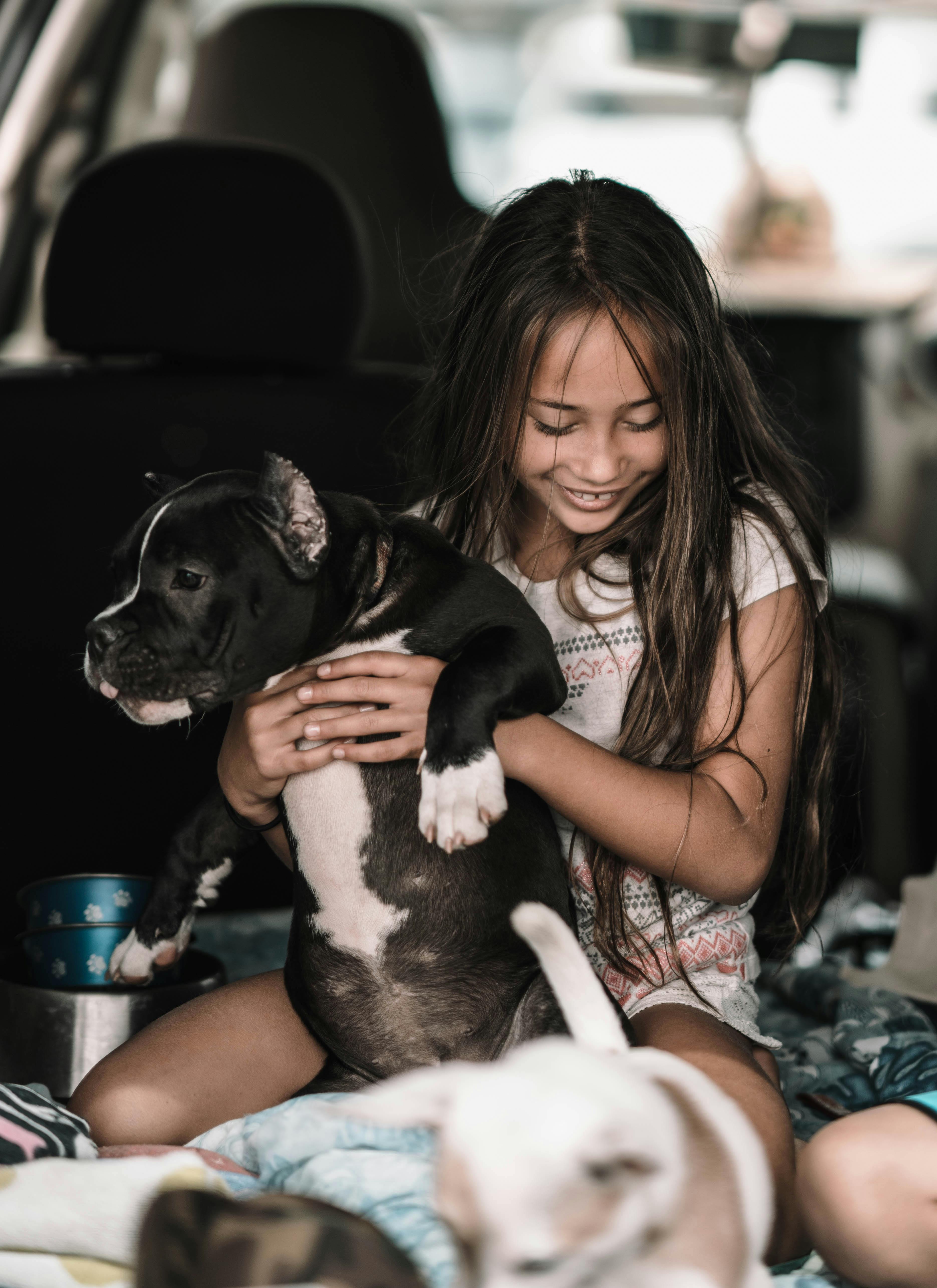 Girl Holding Puppy Inside Van