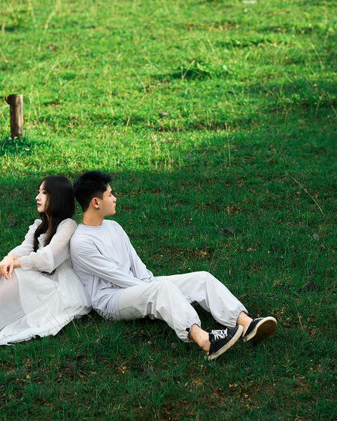 Couple Sitting Back to Back on Grass