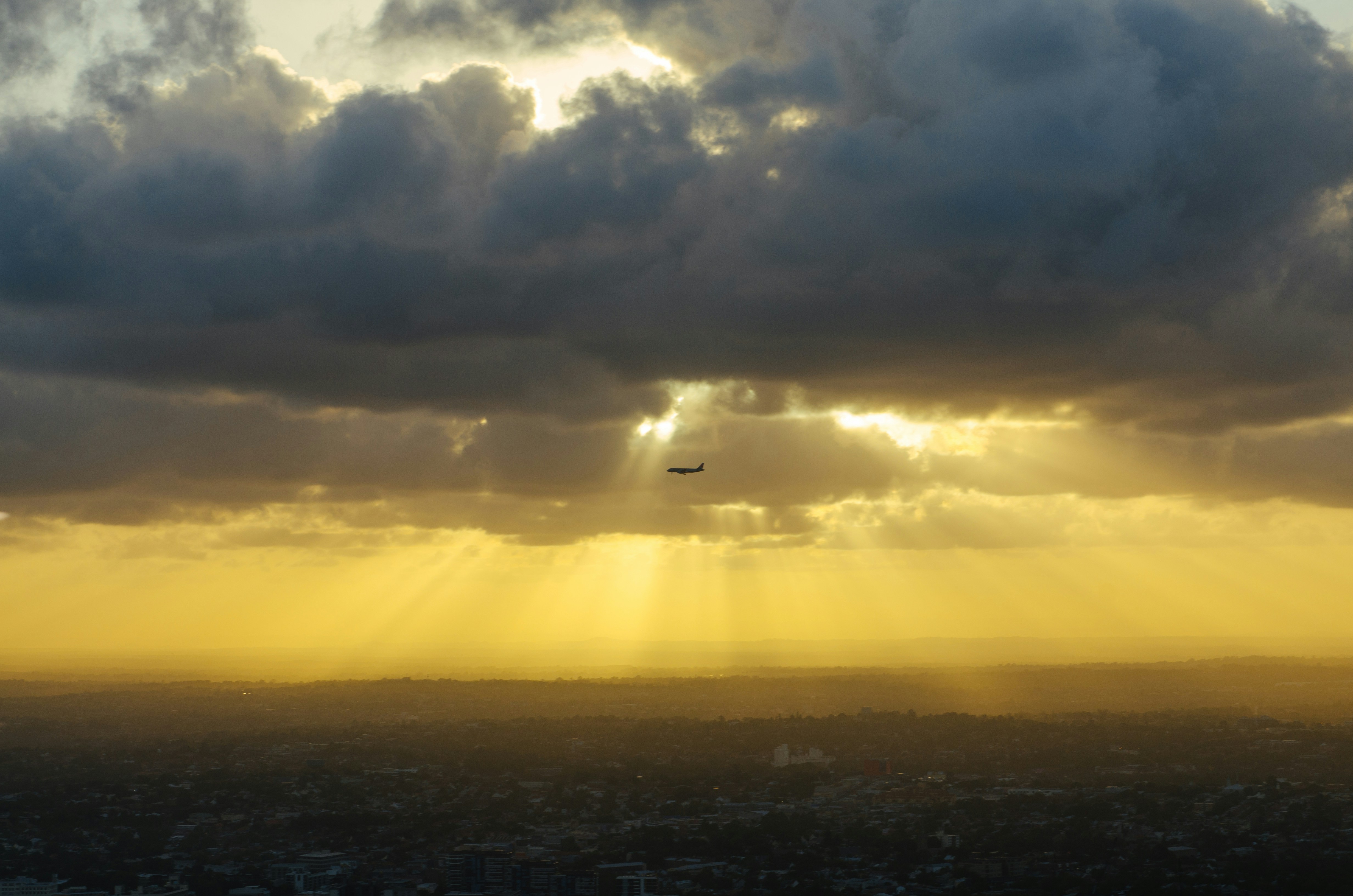Airplane Over City at Golden Sunset
