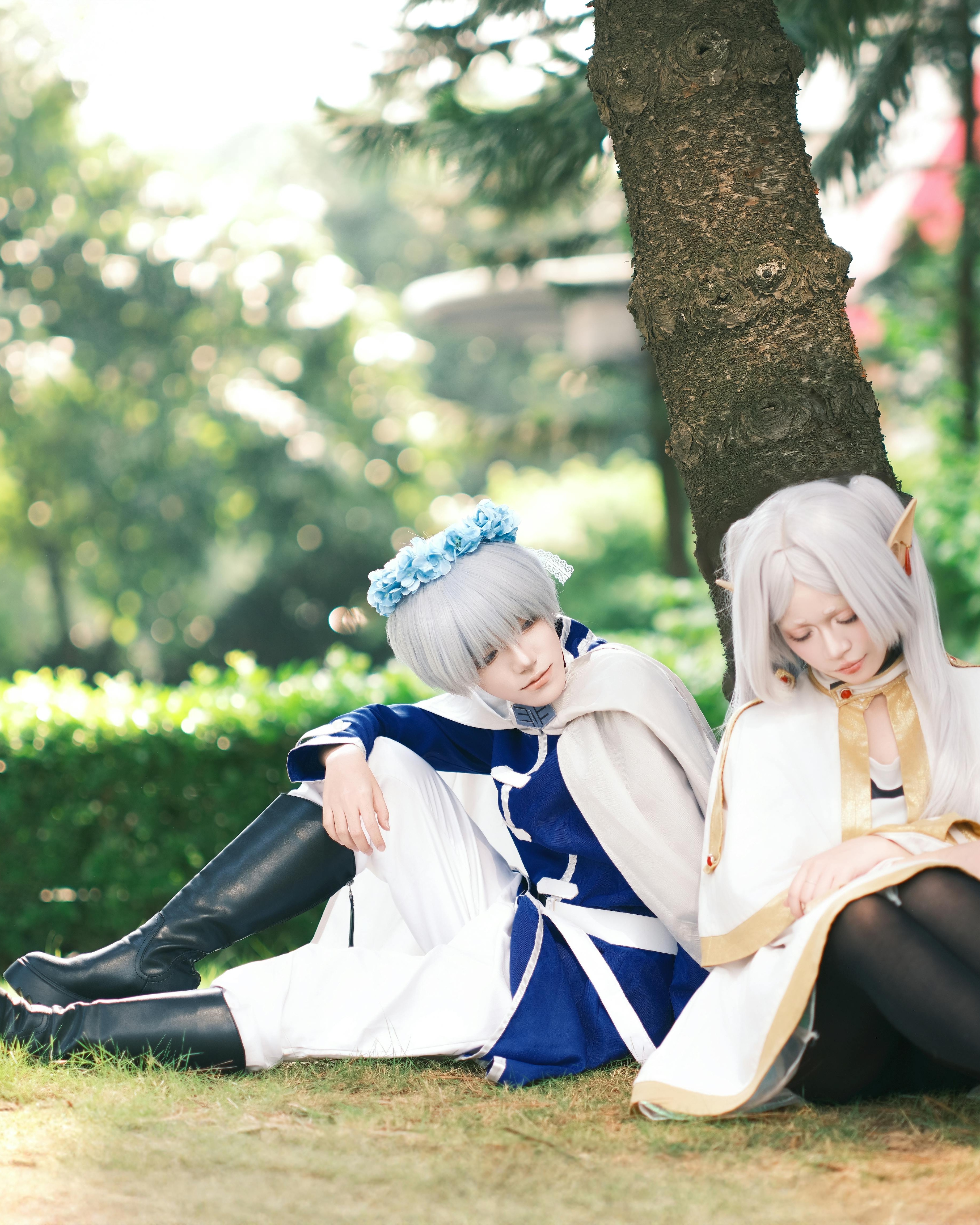 Two cosplayers resting under a tree