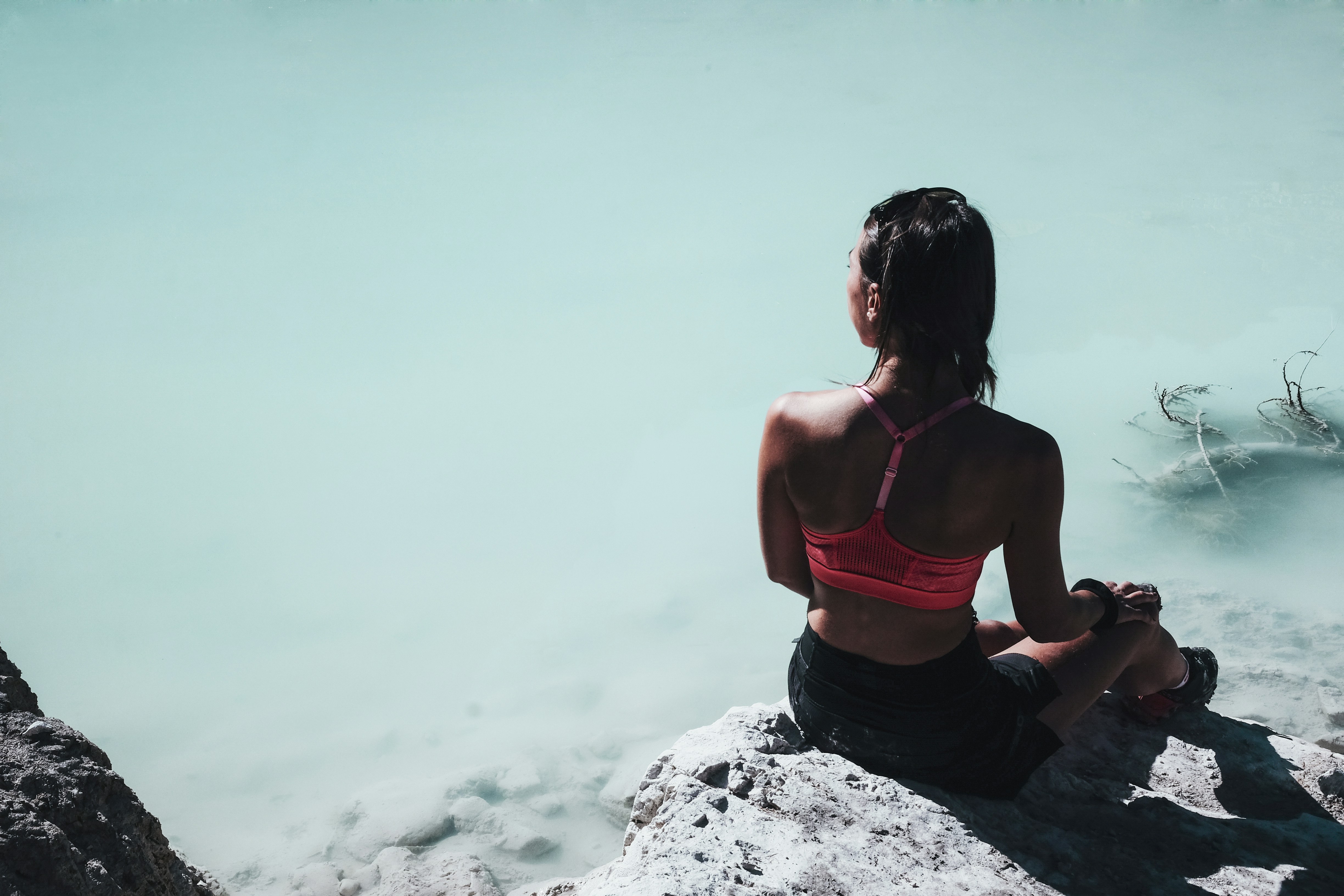 Woman Sitting By Turquoise Lake