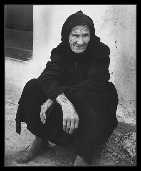 Elderly Woman Squatting by Wall