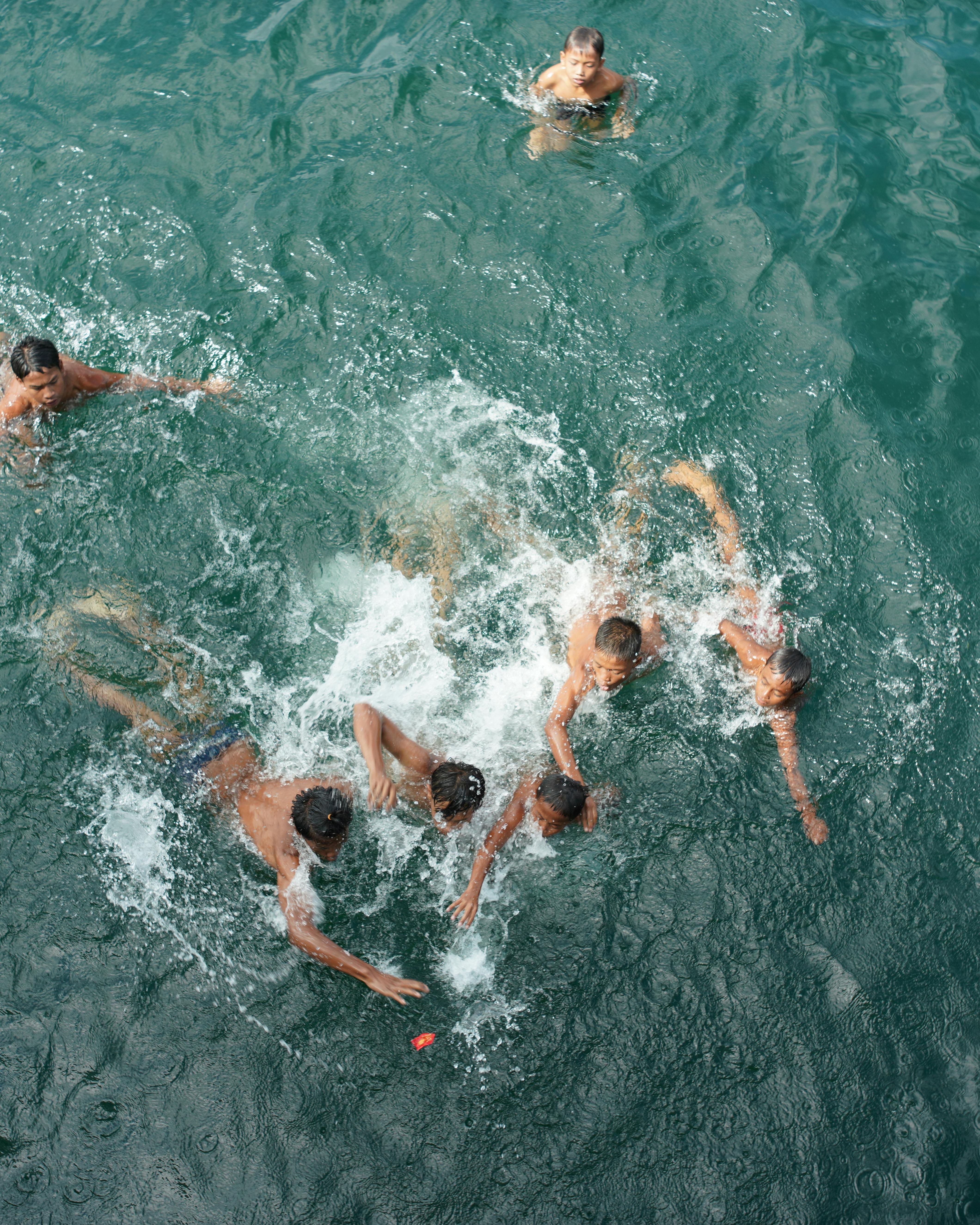 Boys Chasing Red Object in Water